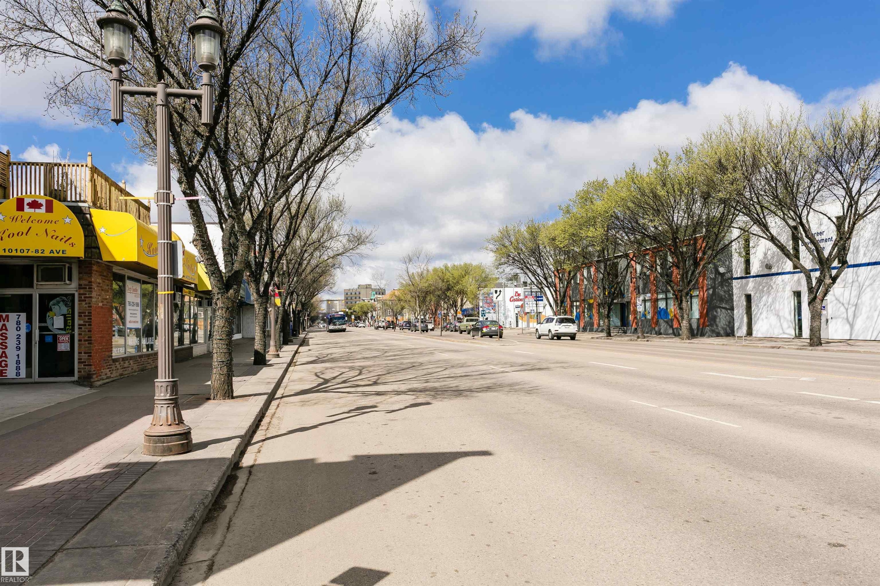 Street-level commercial buildings featuring brick facades, prominent signage, and mature trees lining the sidewalk - 10035 81 Avenue Nw, Edmonton, AB - Outdoor