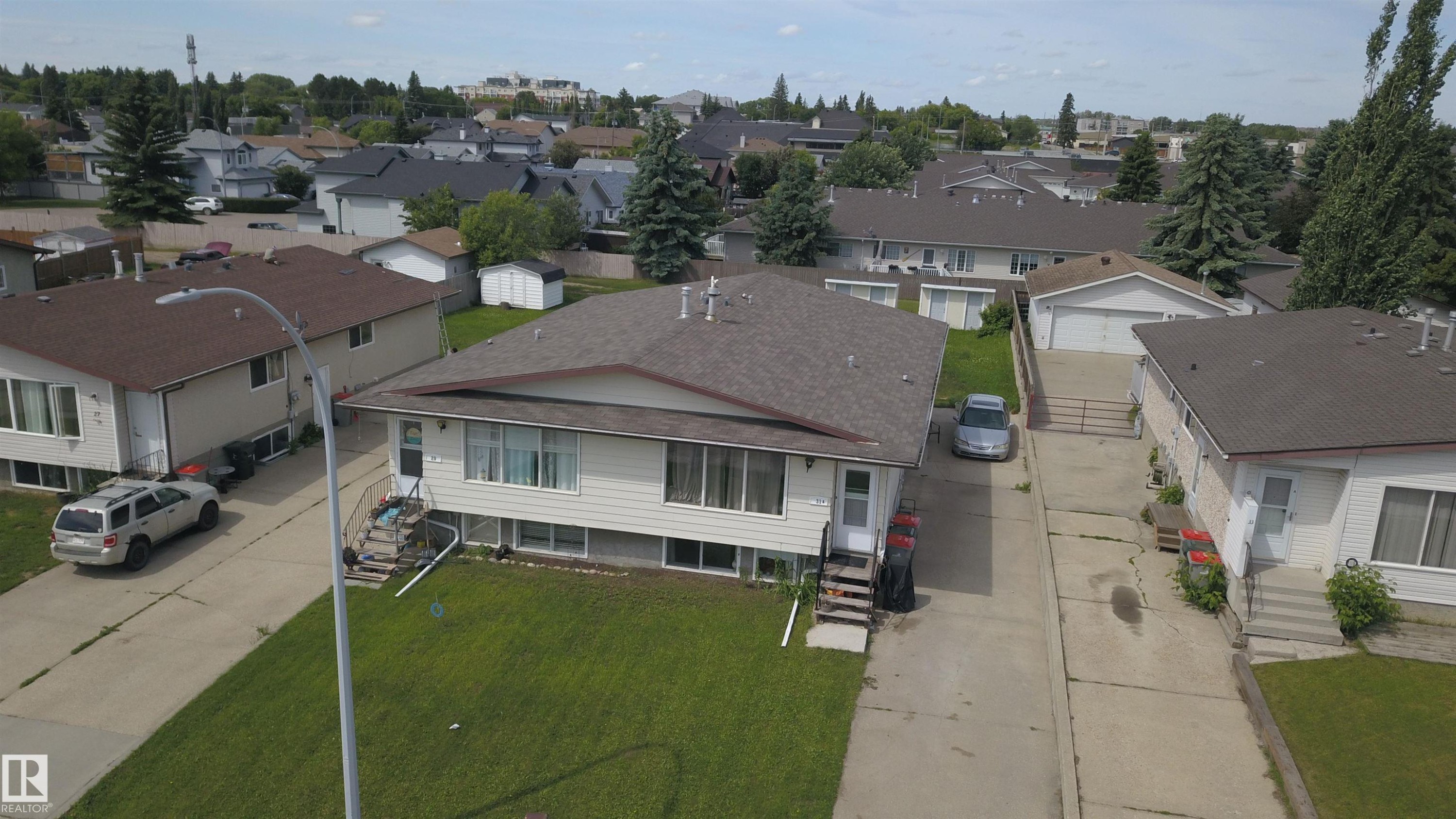 Single-story residence featuring light-colored siding, a dark shingle roof, and a mature green lawn - 31 Brown Street, Stony Plain, AB