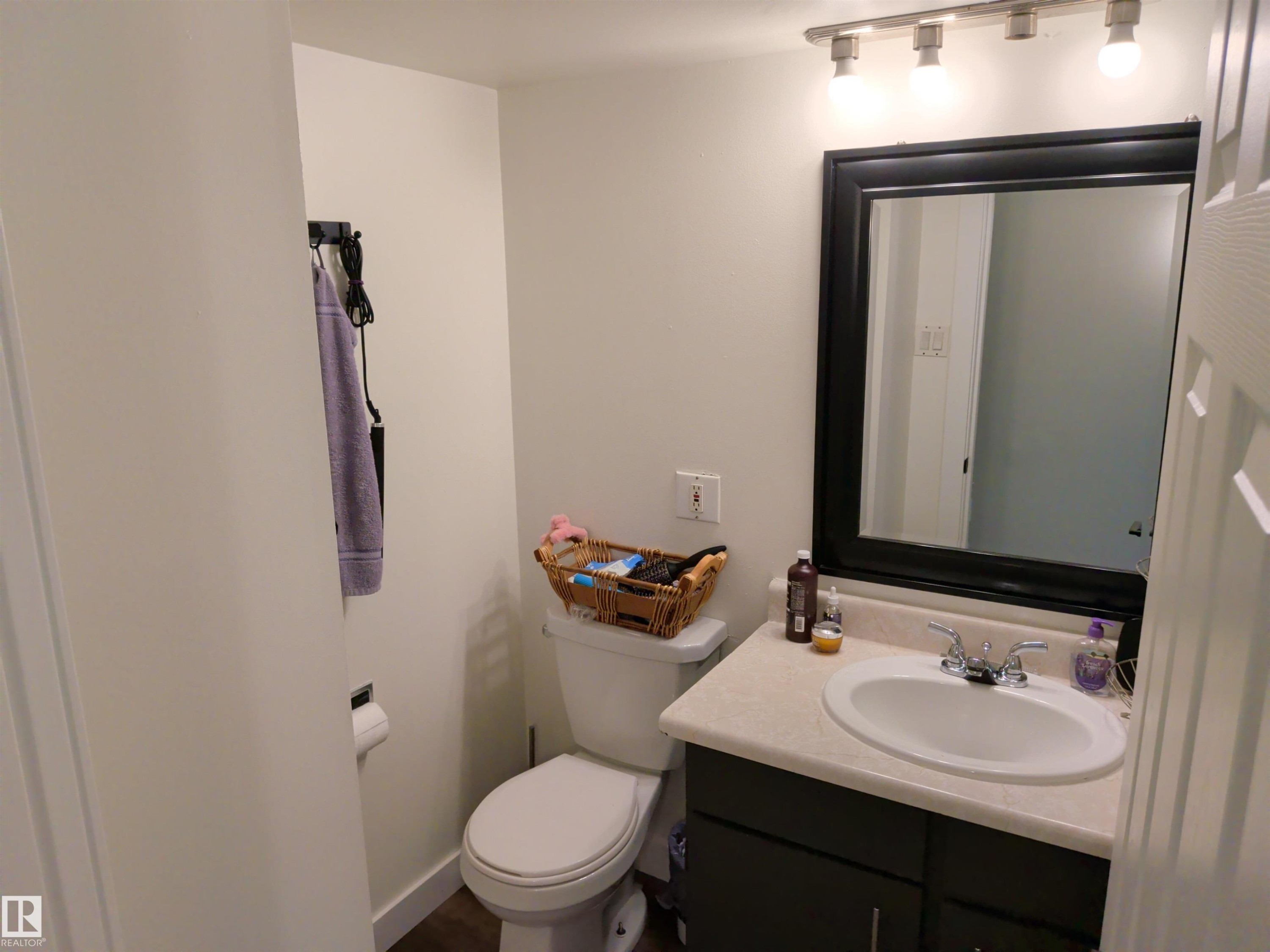 Bathroom featuring a single vanity with an integrated sink, dark cabinet base, and a light-toned countertop - 31 Brown Street, Stony Plain, AB