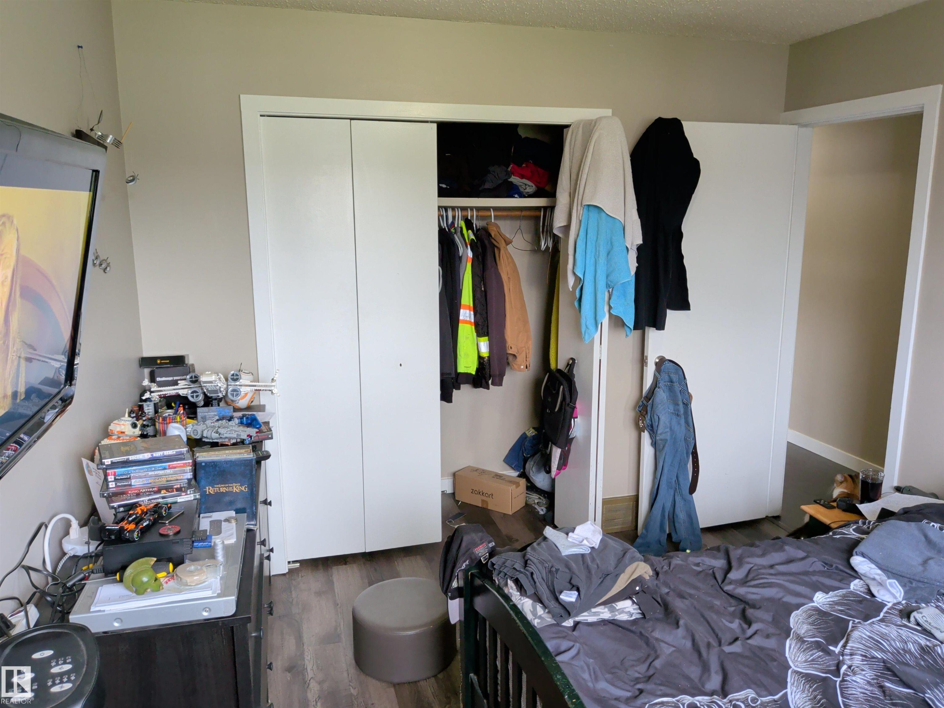 Room featuring wood-finish flooring, neutral wall paint, and a built-in closet with white bifold doors - 31 Brown Street, Stony Plain, AB