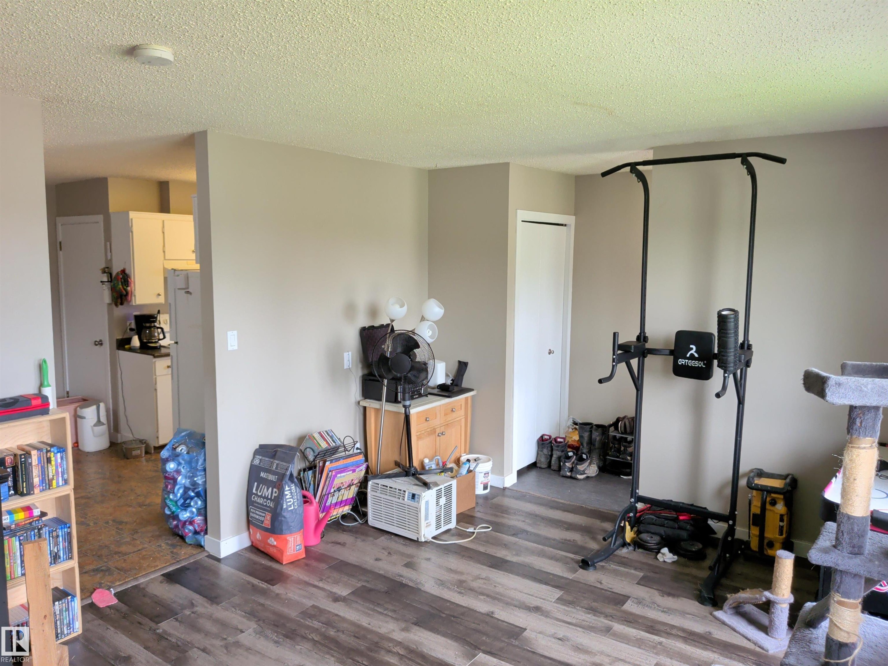 Open living space featuring wood-finish flooring, neutral wall tones, and a textured ceiling - 31 Brown Street, Stony Plain, AB