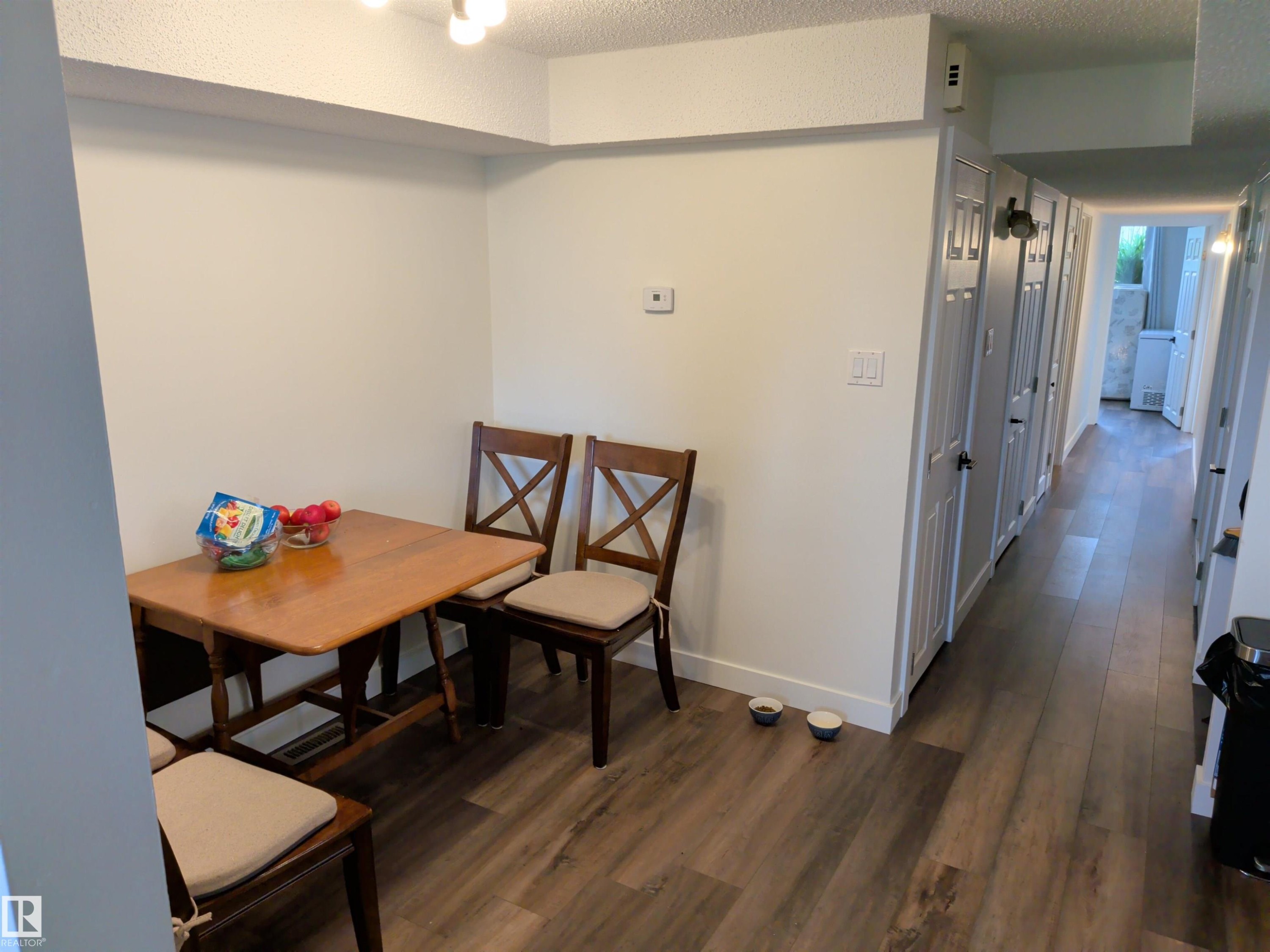 Interior space featuring wood-finish flooring, white baseboards, and a series of white paneled doors with dark hardware along a hallway - 31 Brown Street, Stony Plain, AB