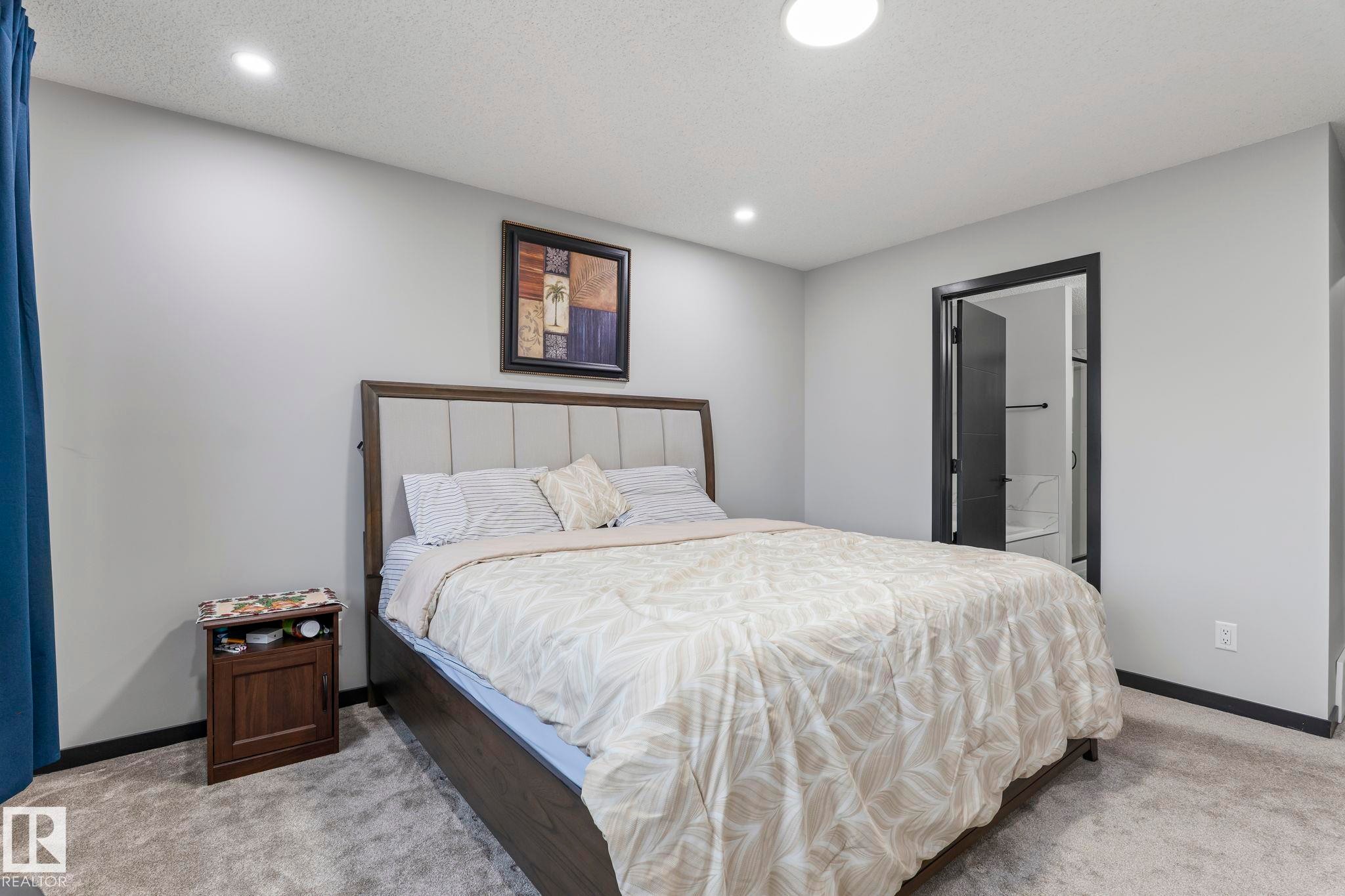 Spacious bedroom featuring light gray walls, plush gray carpeting, and recessed lighting - 5110 23A Ave Sw, Edmonton, AB