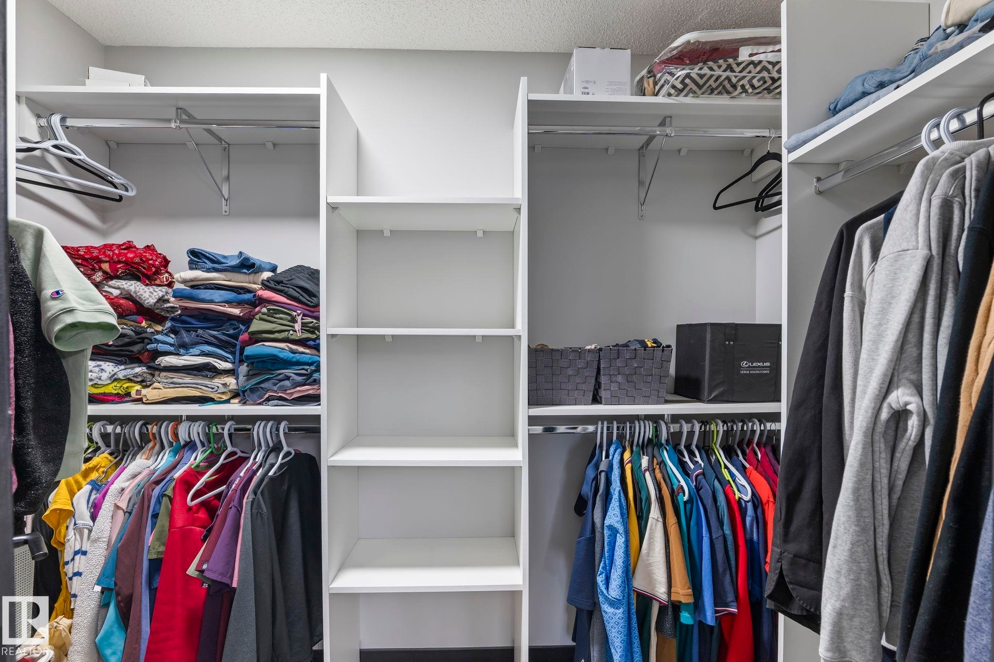 Custom closet organization system featuring white shelving, multiple hanging rods, and integrated vertical storage compartments - 5110 23A Ave Sw, Edmonton, AB
