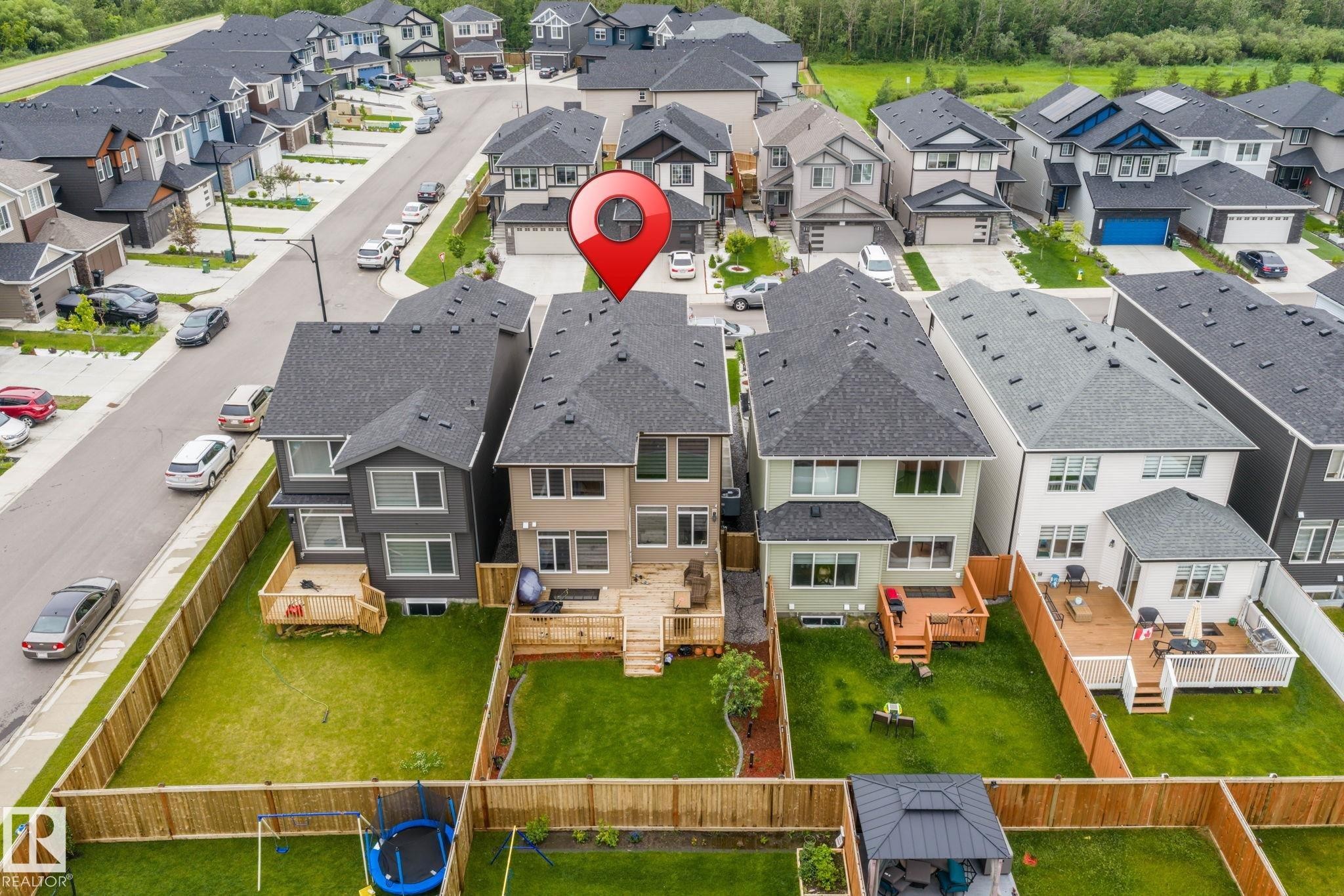 Modern two-story residence featuring a dark shingle roof, light-colored siding, and multiple windows across the rear elevation - 5110 23A Ave Sw, Edmonton, AB