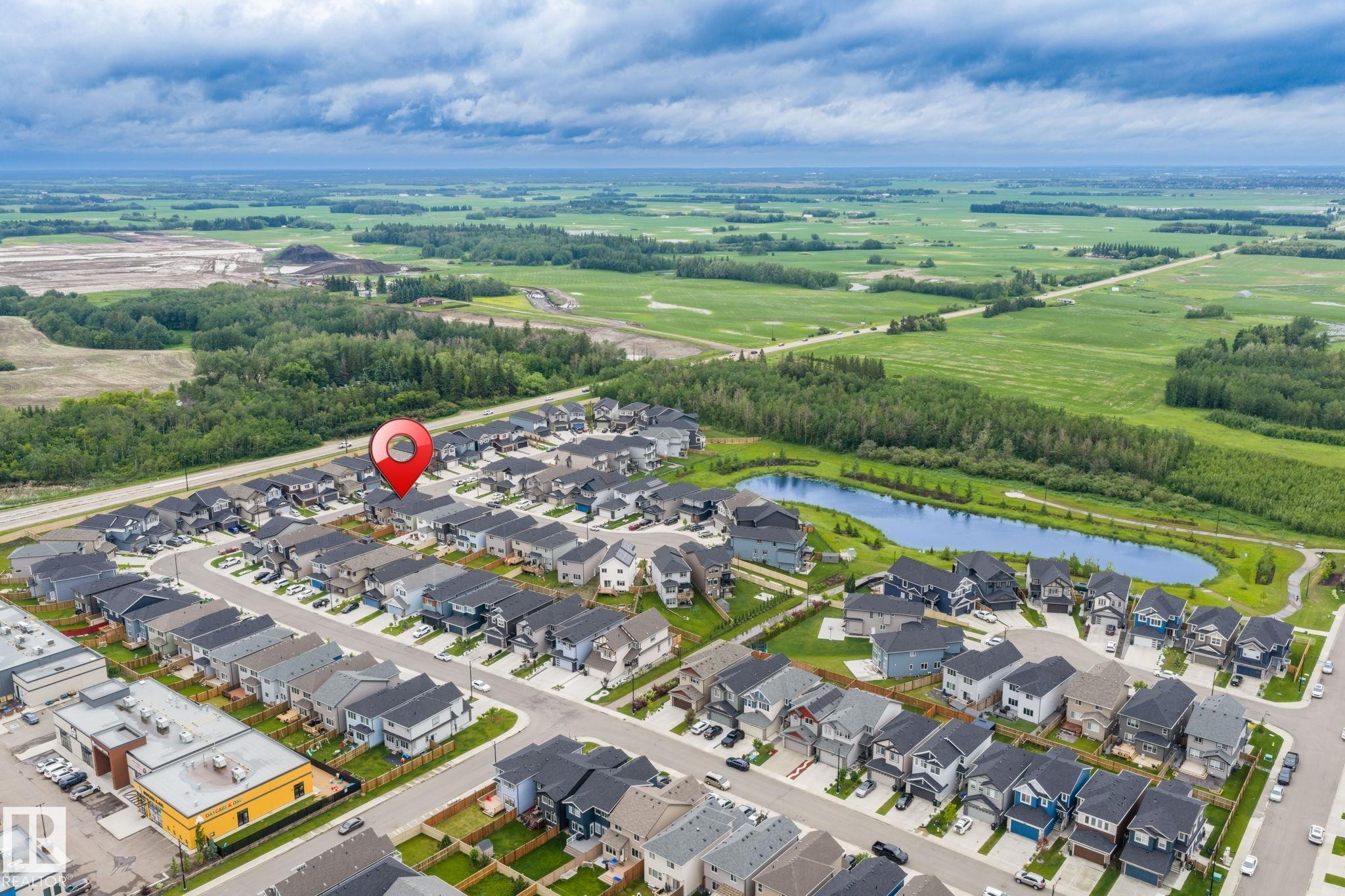 Aerial neighborhood perspective featuring residential properties, a central pond, and surrounding green spaces - 5110 23A Ave Sw, Edmonton, AB