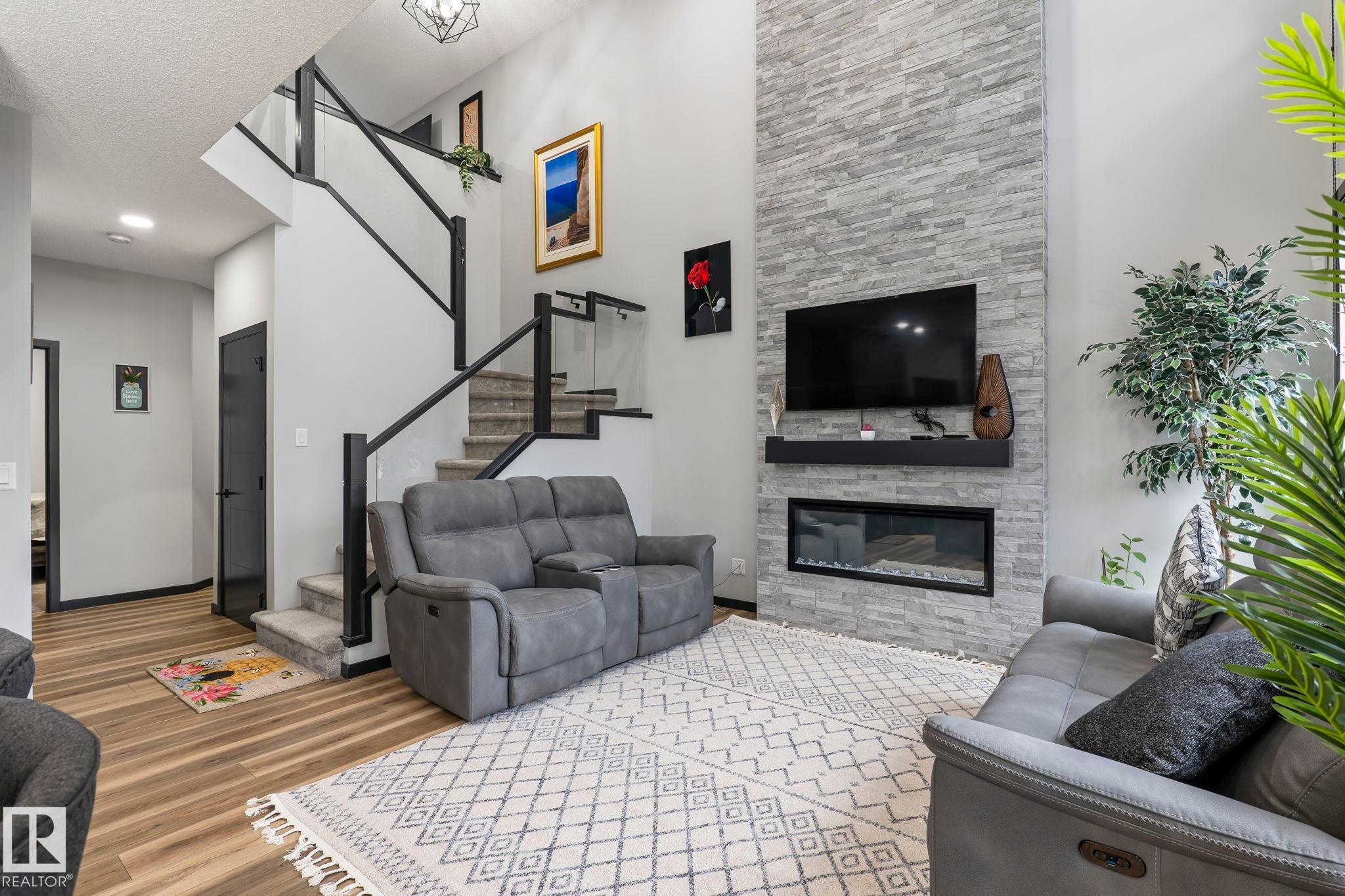 Two-story living area featuring a stacked stone fireplace with a linear insert and a floating mantel - 5110 23A Ave Sw, Edmonton, AB