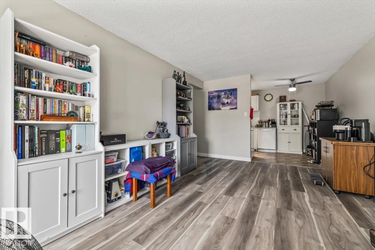 Open-concept living area featuring wood-finish flooring, neutral wall tones, and a textured ceiling - #202 10330 113 St Nw, Edmonton, AB