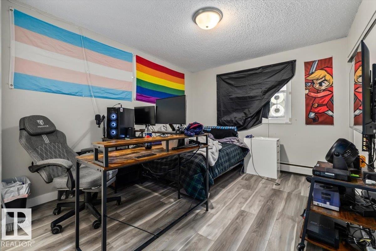 Bedroom featuring wood-finish flooring, a window with a dark covering, and a ceiling-mounted light fixture - #202 10330 113 St Nw, Edmonton, AB
