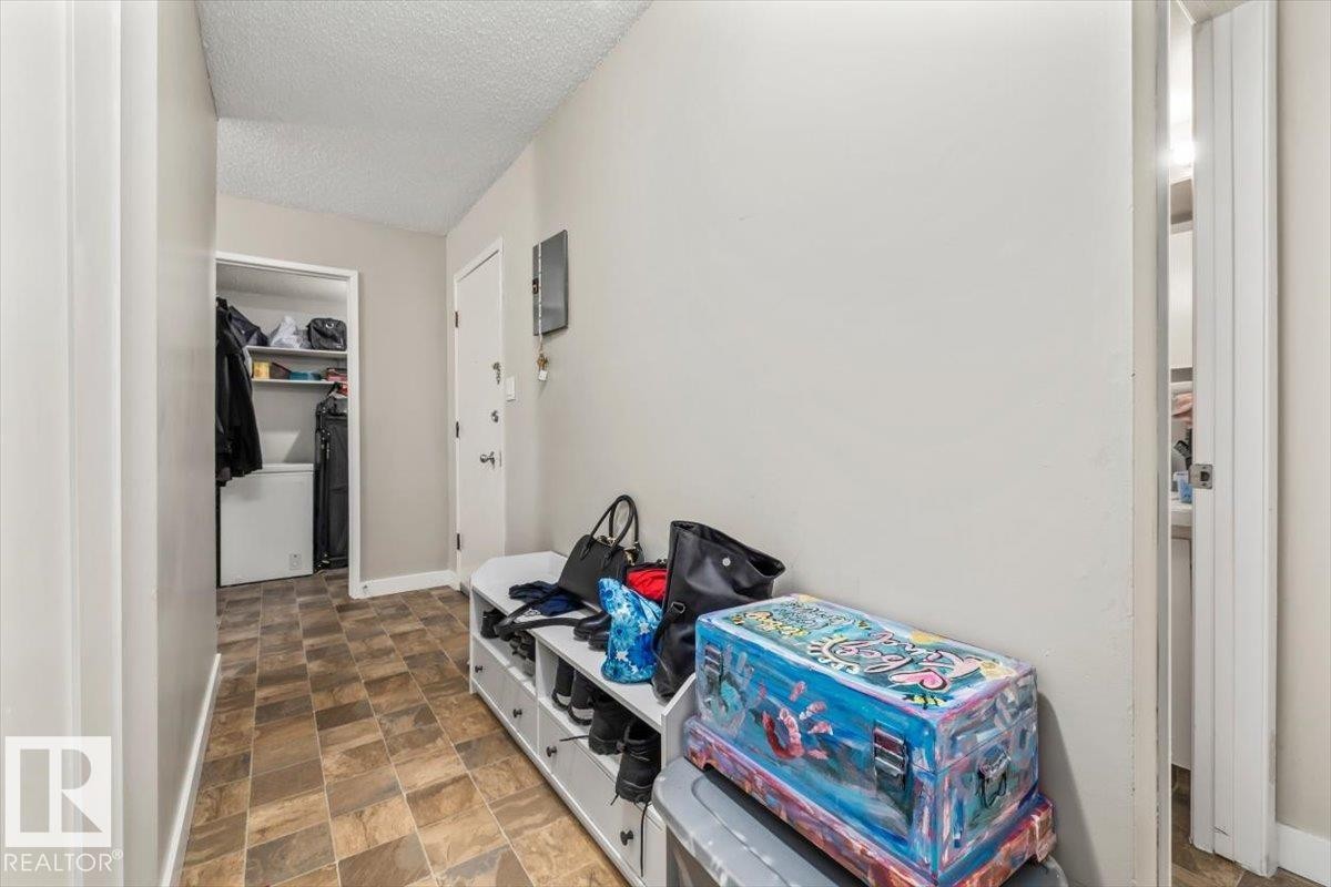 Entryway featuring neutral wall paint, textured ceiling, tiled flooring, and a white door with silver hardware - #202 10330 113 St Nw, Edmonton, AB