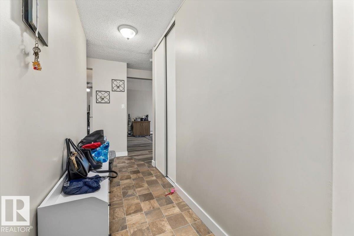 Entryway featuring textured ceiling, flush-mount lighting, and durable tiled flooring - #202 10330 113 St Nw, Edmonton, AB