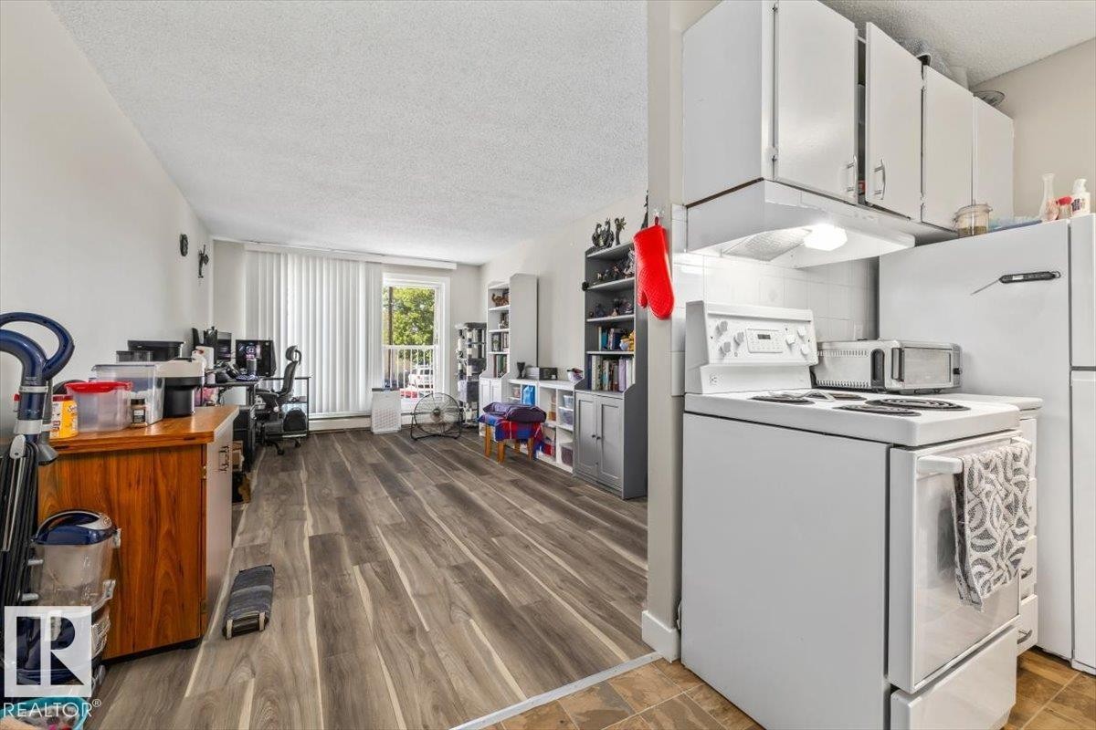 Kitchenette with white cabinetry, included range, and refrigerator - #202 10330 113 St Nw, Edmonton, AB