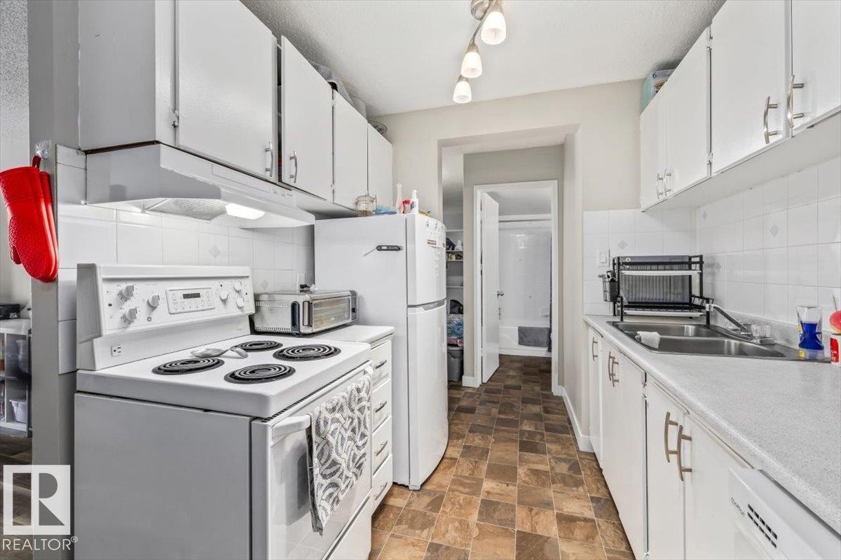 Compact kitchen featuring white cabinetry, a white electric range, and a white refrigerator - #202 10330 113 St Nw, Edmonton, AB