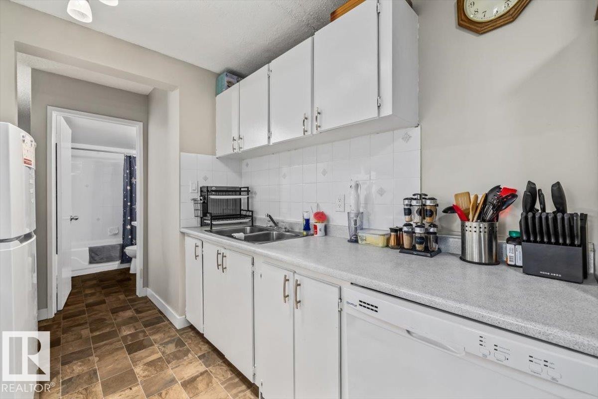 Efficient kitchen featuring white cabinetry, a double basin sink, and white appliances - #202 10330 113 St Nw, Edmonton, AB