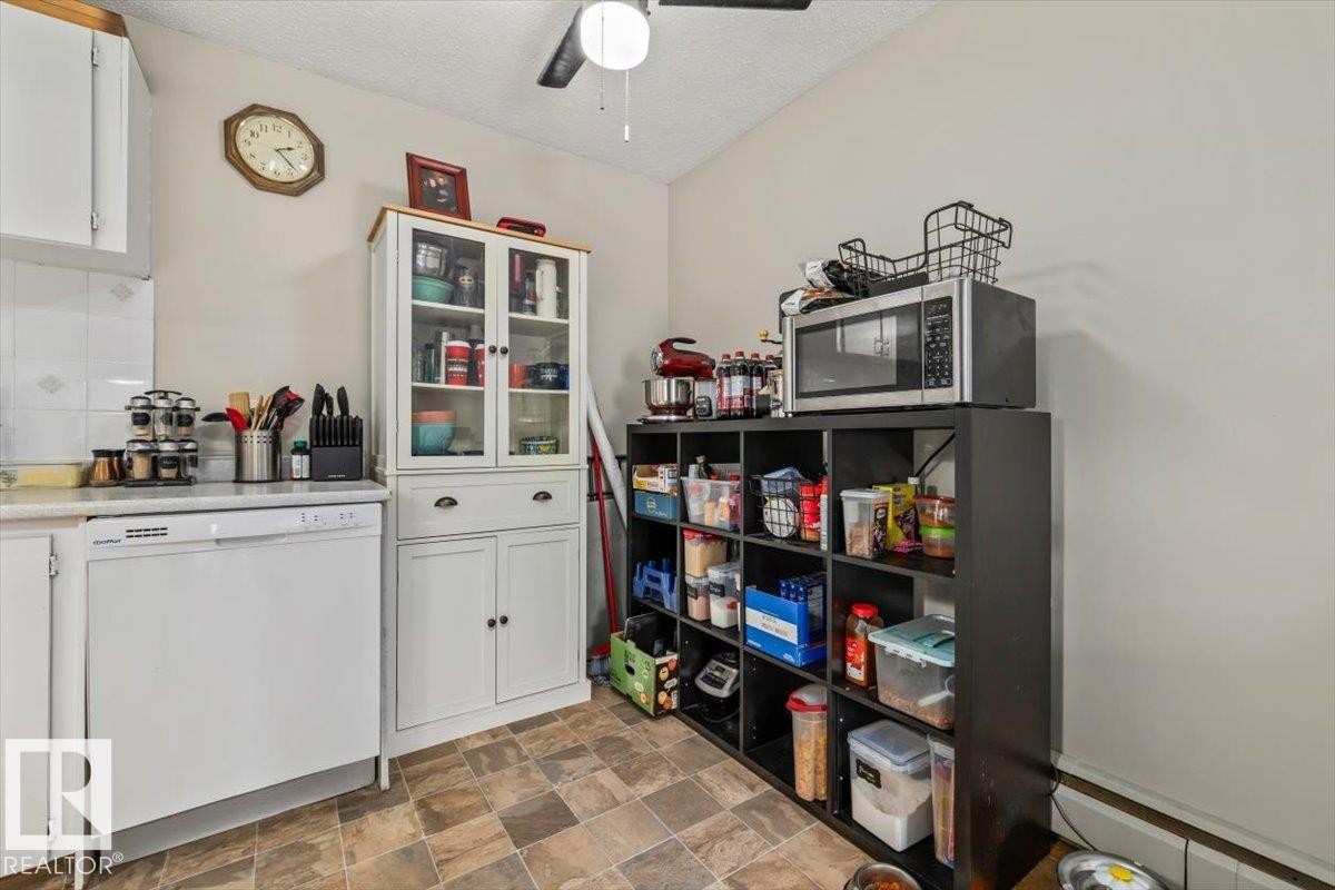 Kitchen featuring a built-in dishwasher, white cabinetry, and a ceiling fan - #202 10330 113 St Nw, Edmonton, AB