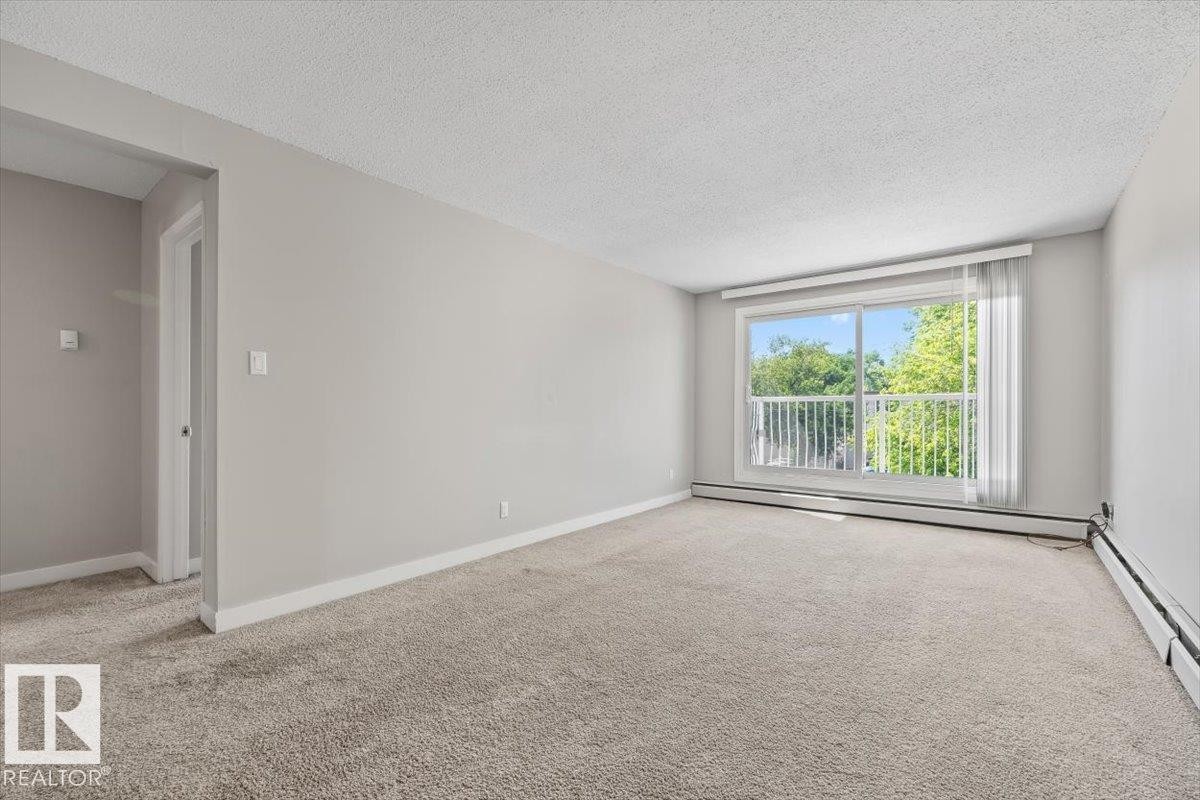 Spacious interior room with light-colored carpet flooring and neutral wall finishes - #306 10330 113 St Nw, Edmonton, AB