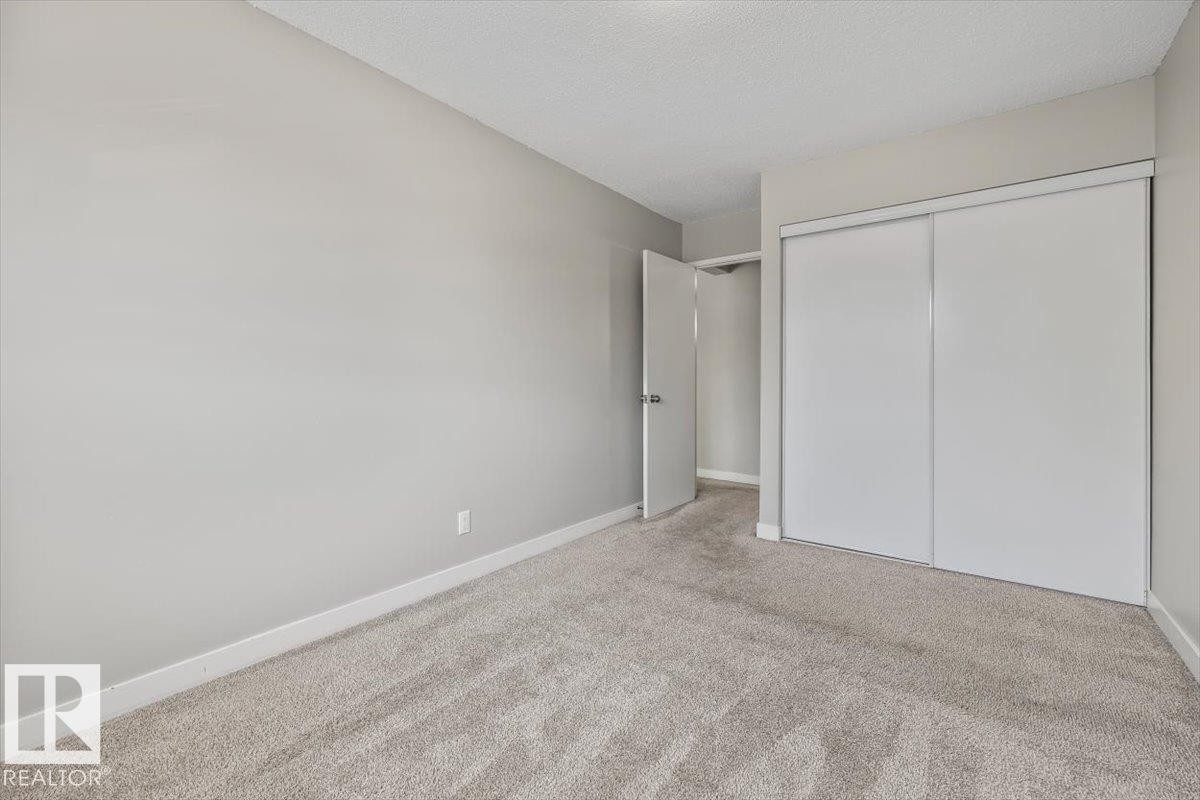 Bedroom featuring plush carpeting, light gray wall paint, and white trim - #306 10330 113 St Nw, Edmonton, AB