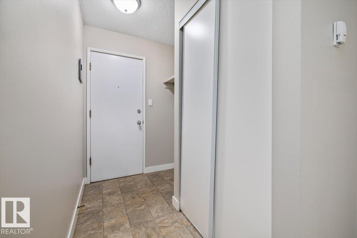 Entryway featuring tile flooring, white interior door with hardware, overhead flush-mount lighting, and sliding closet doors - #306 10330 113 St Nw, Edmonton, AB