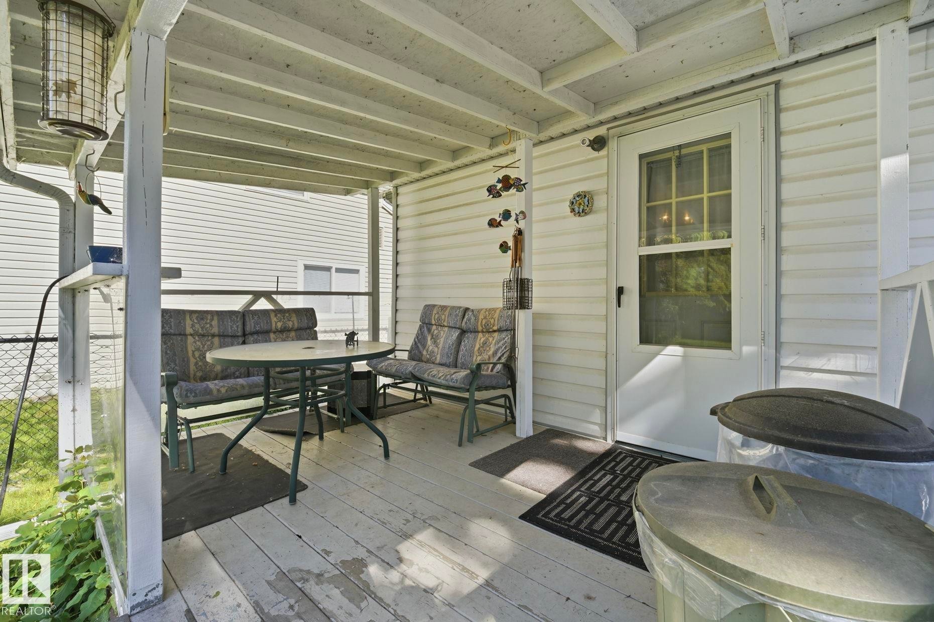 Covered porch featuring white siding, exposed ceiling joists, white painted wood-finish flooring, and direct exterior access - 1410 47436 Range Rd. 15, Rural Leduc County, AB