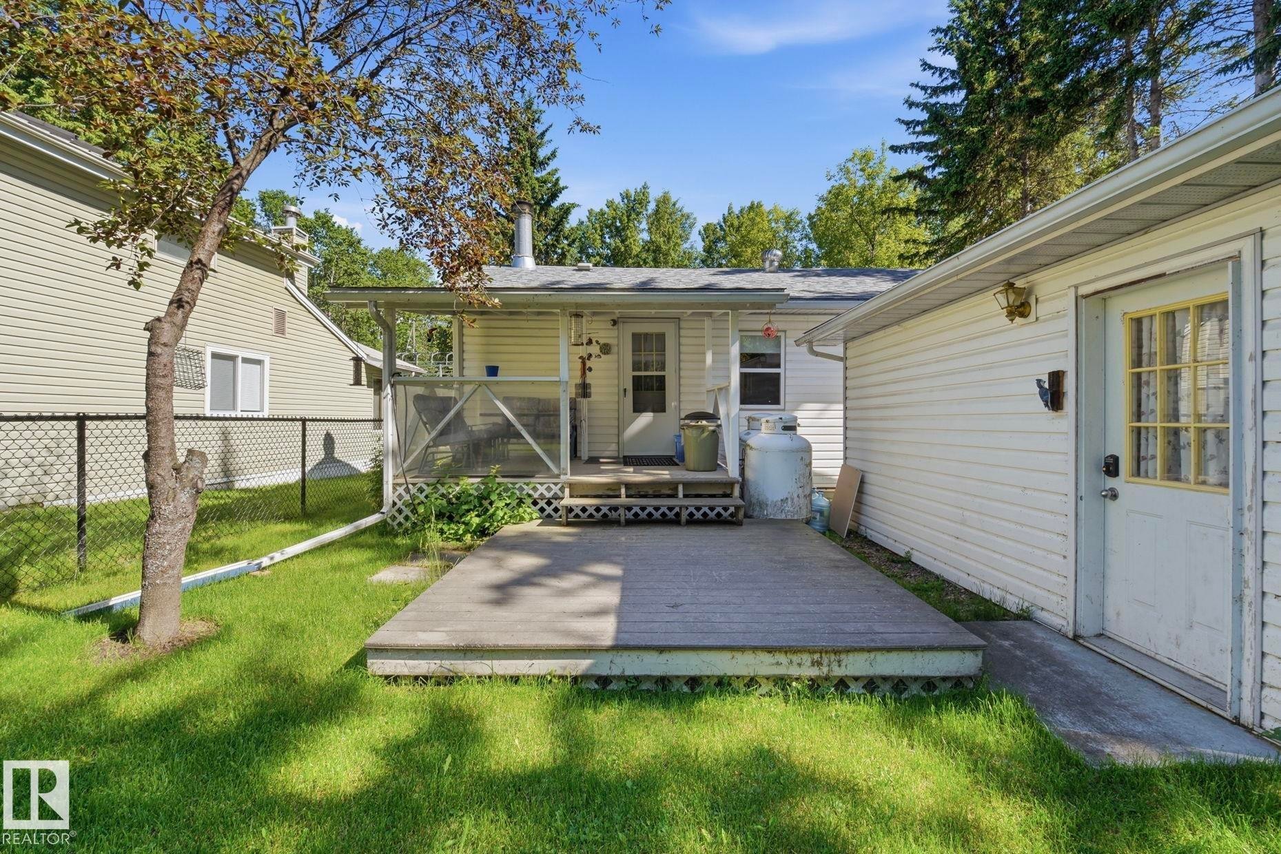Backyard featuring an expansive wood deck, covered porch, and detached garage with an exterior door - 1410 47436 Range Rd. 15, Rural Leduc County, AB