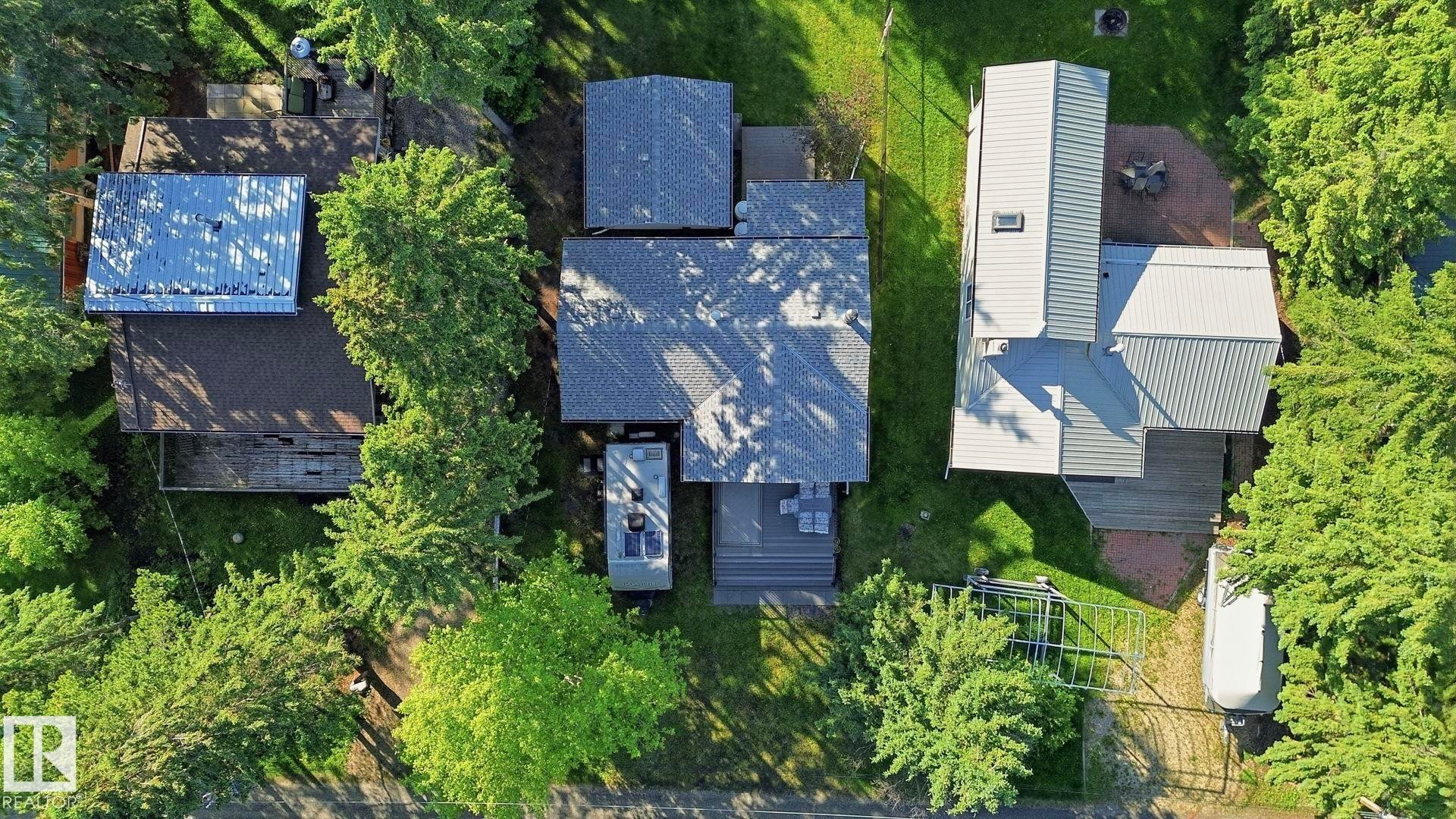 Property featuring an asphalt shingle roof, a multi-level deck, and surrounding mature trees - 1410 47436 Range Rd. 15, Rural Leduc County, AB