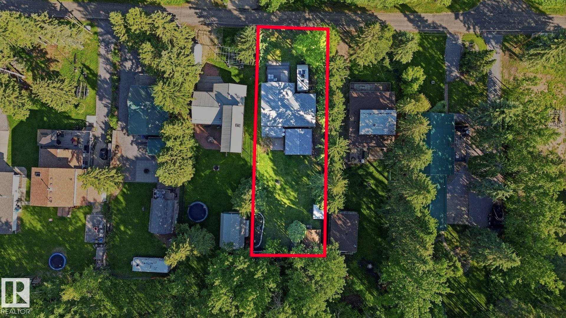 Overhead perspective of a residential property featuring a gray-roofed structure surrounded by mature trees and green landscaping - 1410 47436 Range Rd. 15, Rural Leduc County, AB