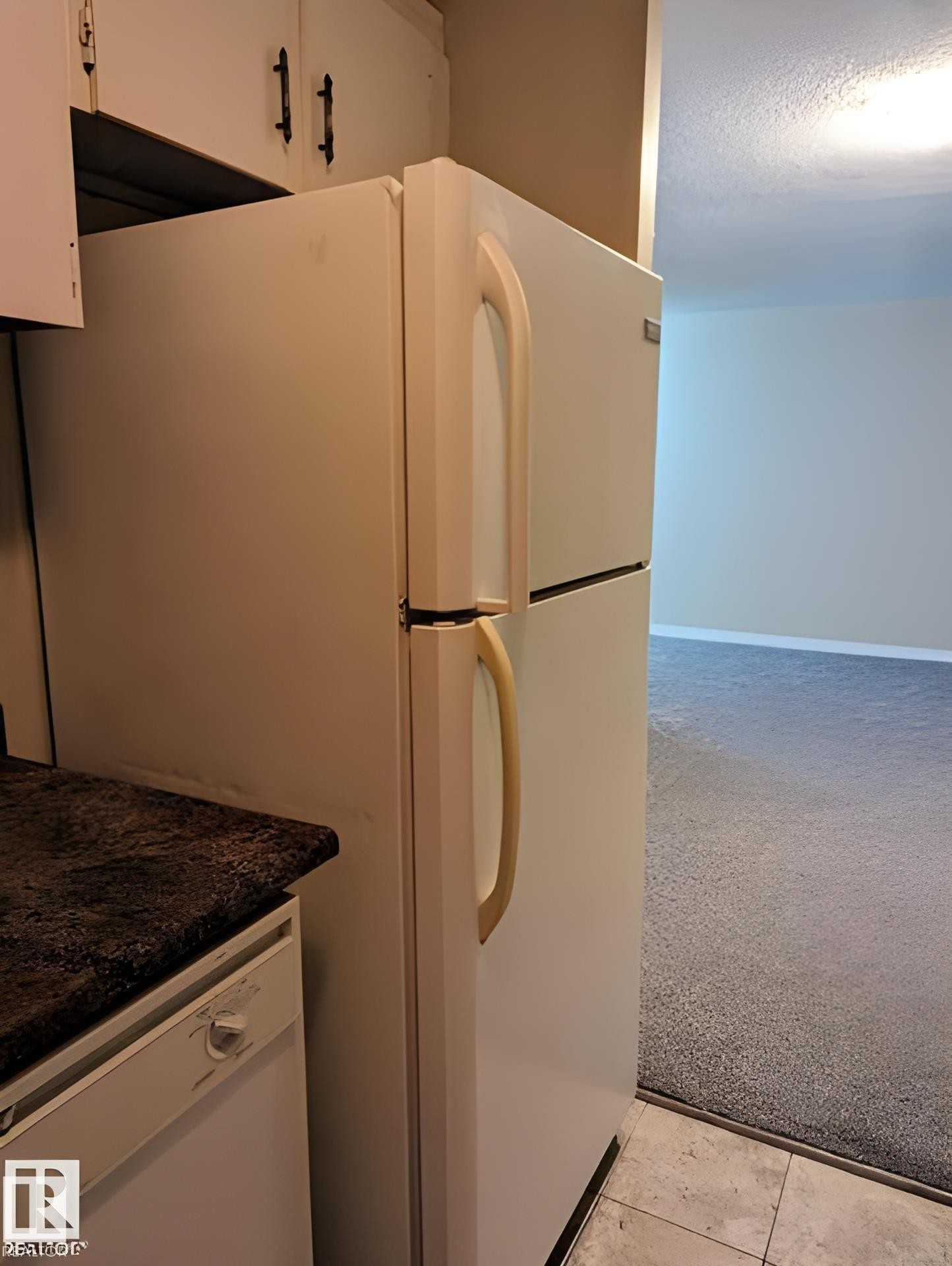 Kitchen area featuring a white refrigerator, upper cabinetry with black hardware, dark speckled countertops, and a white dishwasher - 611 12831 66 Street, Edmonton, AB