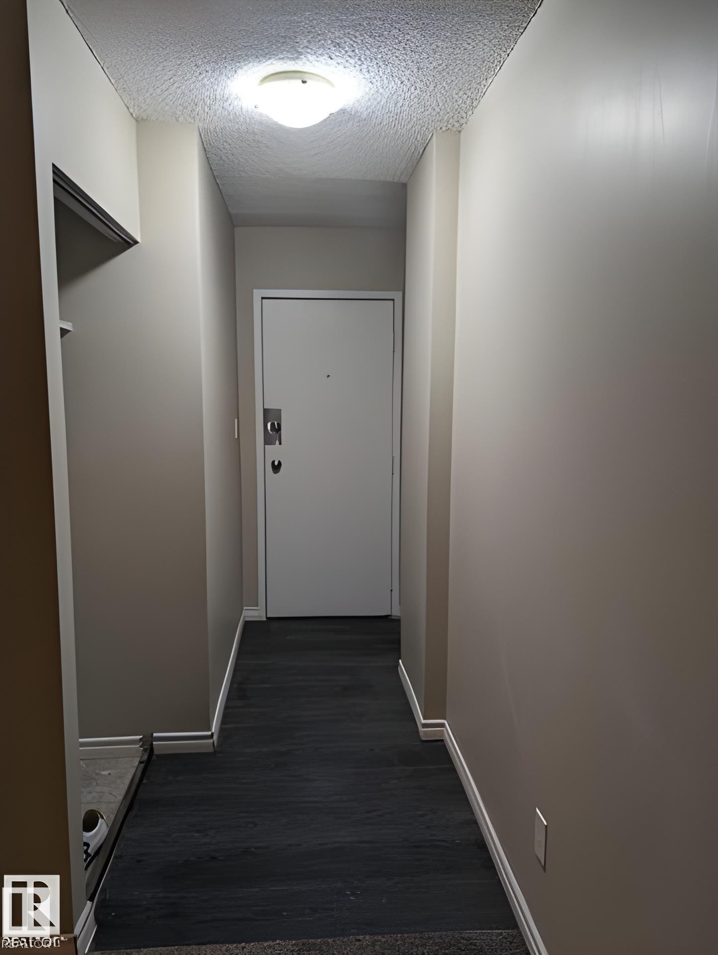 Entryway featuring wood-finish flooring, light tan wall color, a flush-mount ceiling light fixture, and white baseboards - 611 12831 66 Street, Edmonton, AB