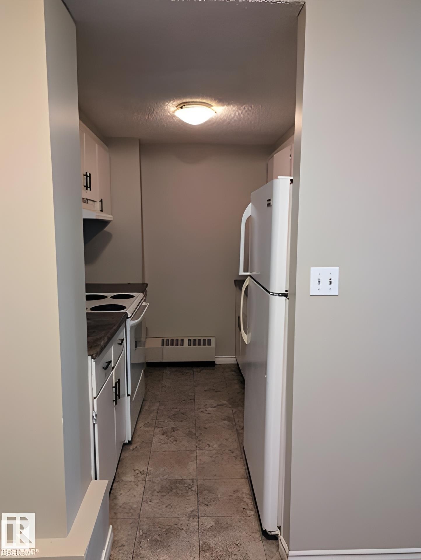 Galley-style kitchen featuring white cabinetry with black hardware, a white electric range, and a white refrigerator - 611 12831 66 Street, Edmonton, AB