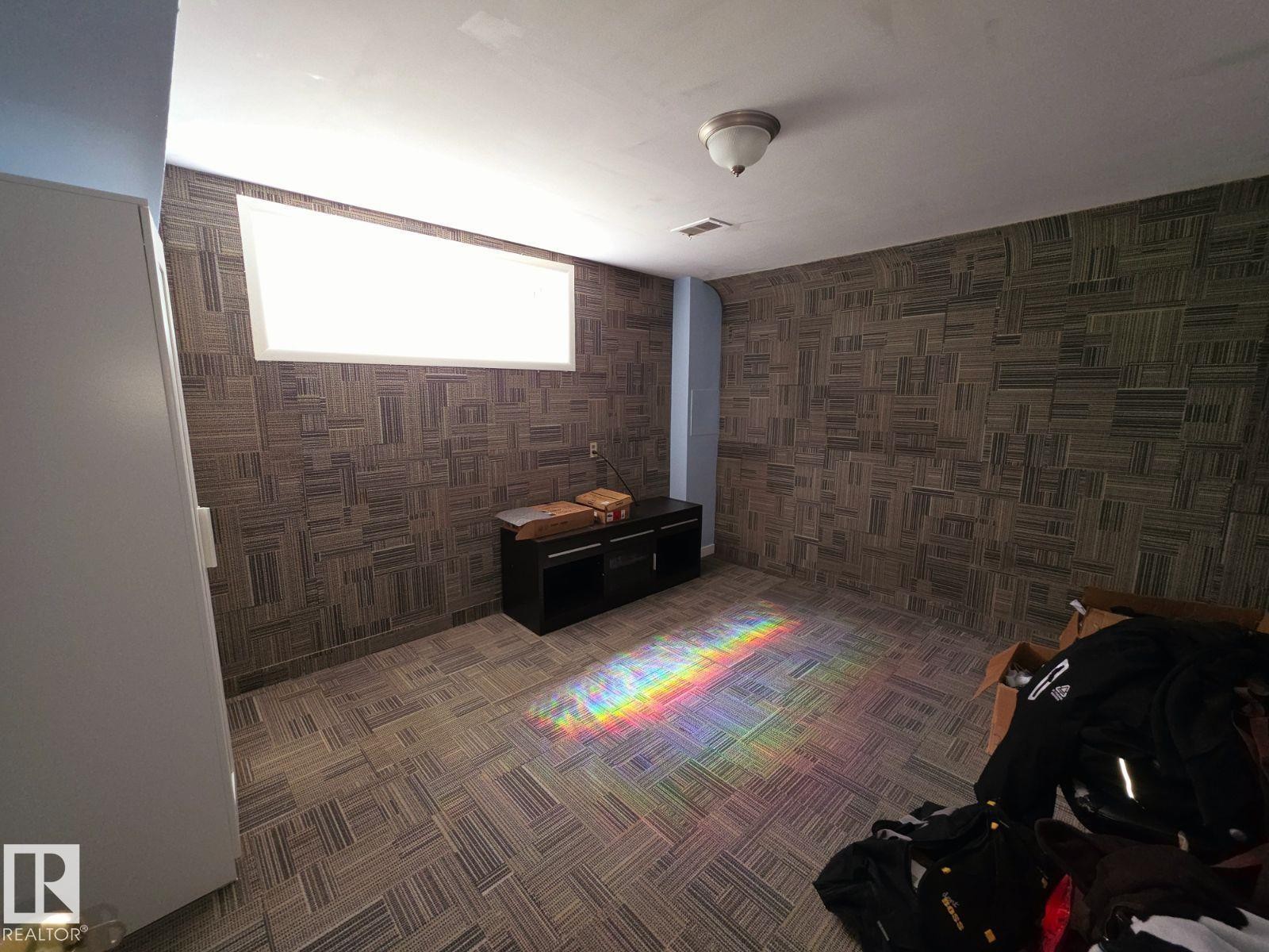 Room featuring patterned wall-to-wall carpeting and walls with a geometric tile pattern - 10404 116 Avenue, Edmonton, AB