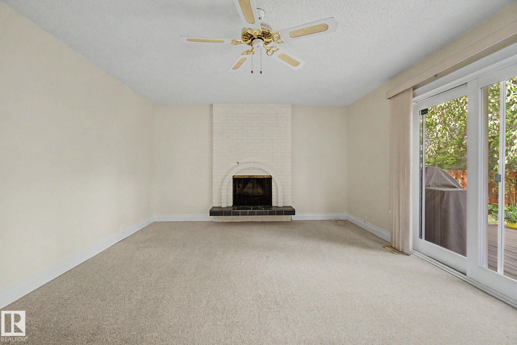 Living area featuring a painted brick fireplace with a dark hearth, ceiling fan, and carpeted flooring - 170 Westridge Rd, Edmonton, AB - Indoor With Fireplace