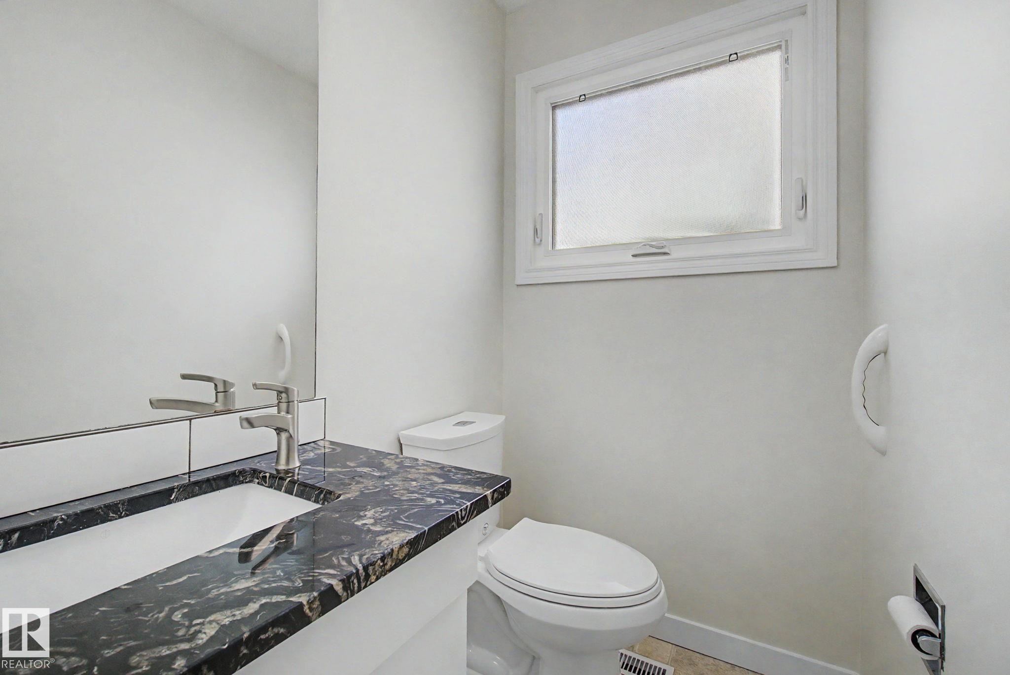 Bathroom vanity with a dark patterned countertop, integrated sink, and brushed nickel faucet - 170 Westridge Rd, Edmonton, AB - Indoor Photo Showing Bathroom