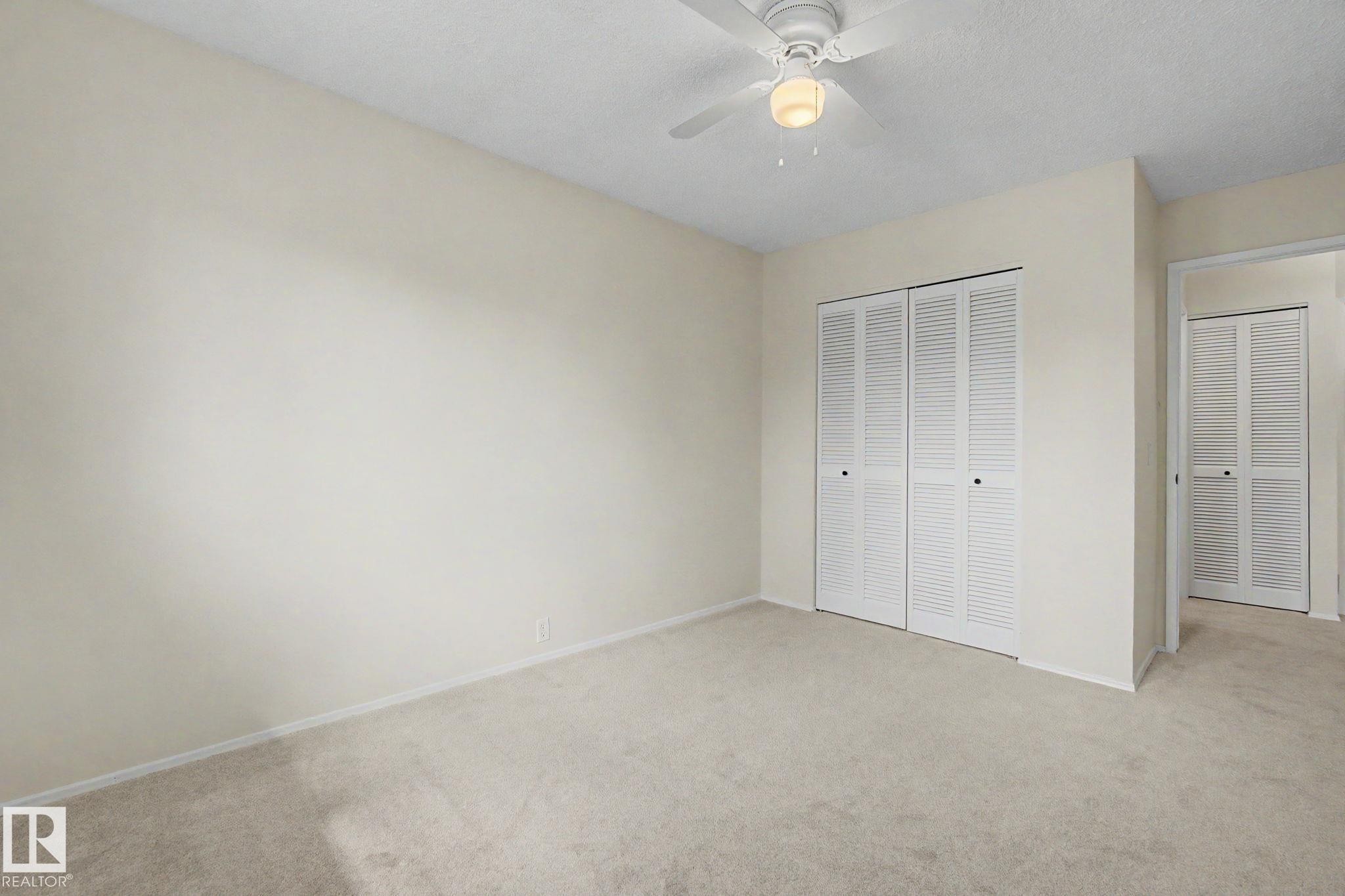 Carpeted room featuring a ceiling fan with light fixture, louvered bi-fold closet doors, and light-toned wall finishes - 170 Westridge Rd, Edmonton, AB - Indoor