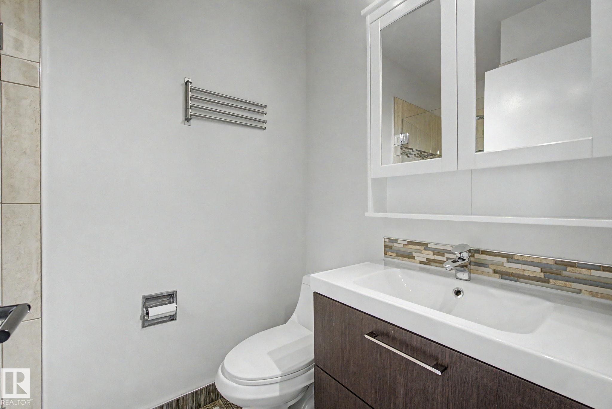 Bathroom vanity featuring a white integrated sink, chrome faucet, and wood-finish cabinetry - 170 Westridge Rd, Edmonton, AB - Indoor Photo Showing Bathroom