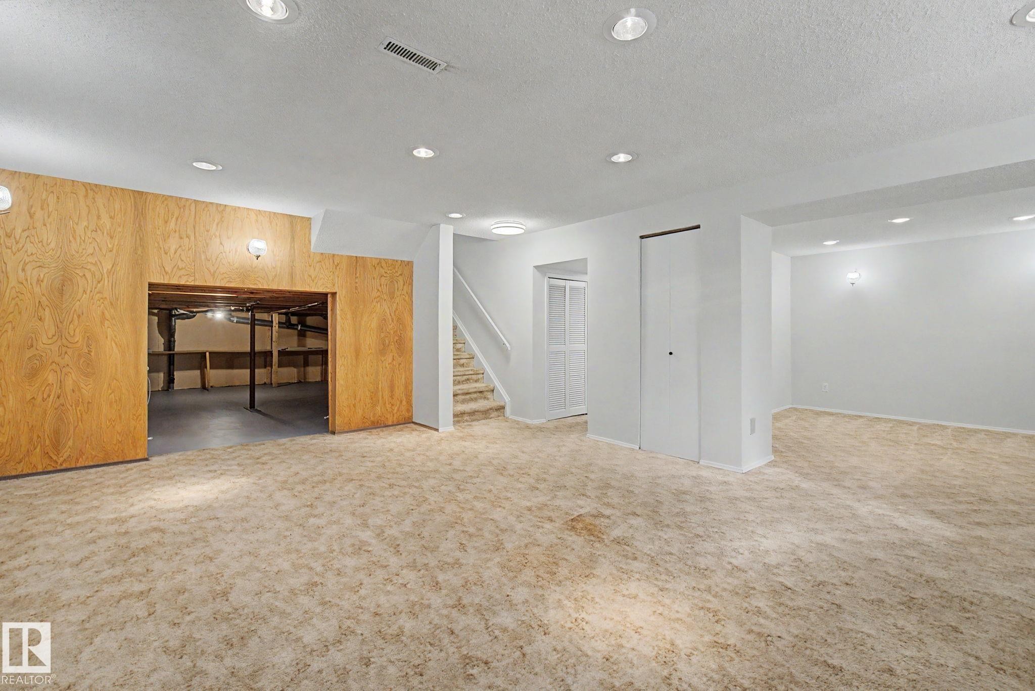 Versatile finished basement featuring recessed lighting, a staircase with carpeted treads, and an unfinished storage area with concrete flooring - 170 Westridge Rd, Edmonton, AB - Indoor Photo Showing Other Room