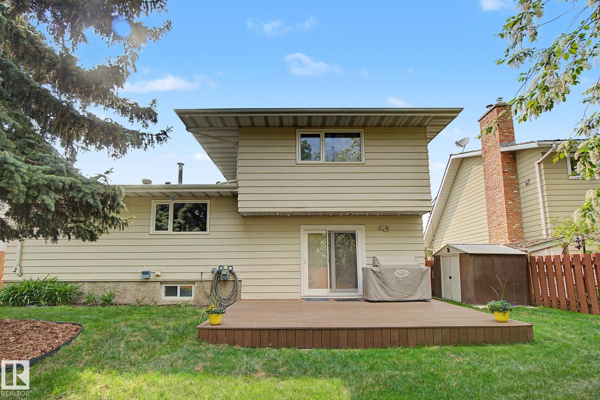 Expansive backyard featuring a composite deck, manicured lawn, mature trees, and a privacy fence - 170 Westridge Rd, Edmonton, AB - Outdoor With Deck Patio Veranda