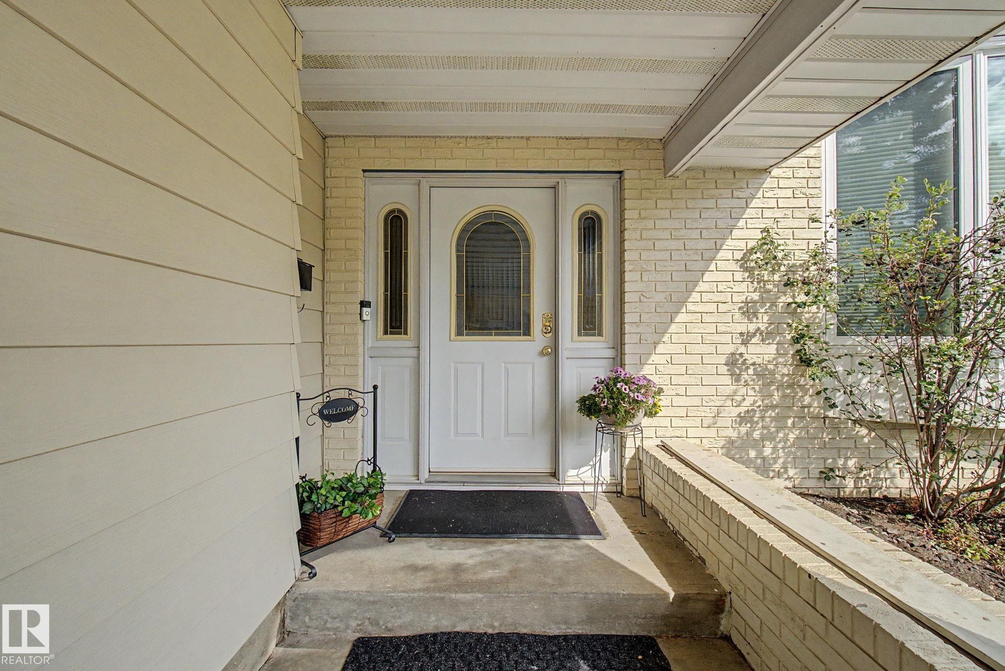 Front entryway featuring a white arch-top door with sidelight windows, light-colored brick facade, and horizontal siding - 170 Westridge Rd, Edmonton, AB - Outdoor With Exterior