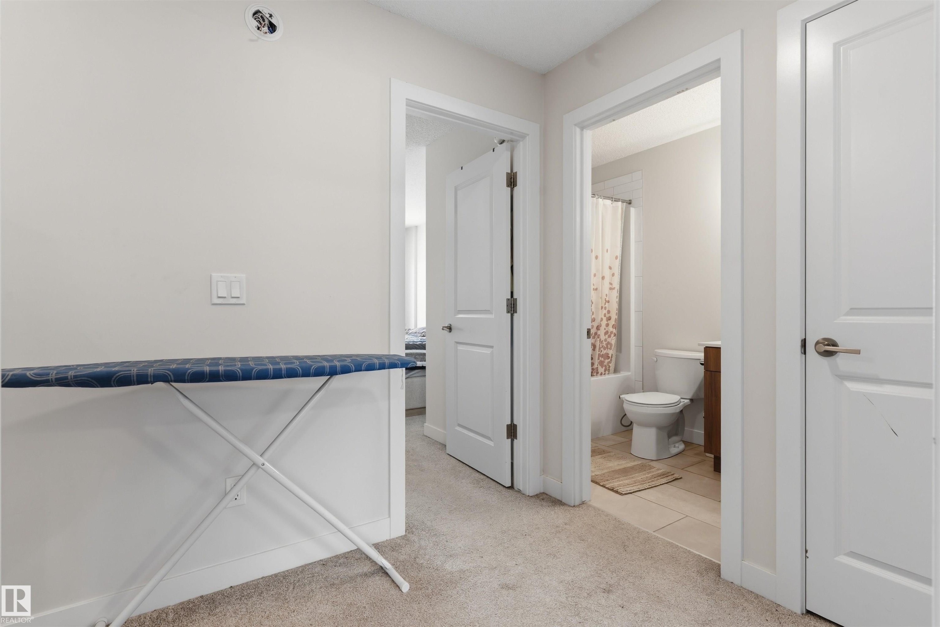 Hallway featuring light beige carpet and multiple white interior doors - 170 804 Welsh Drive, Edmonton, AB