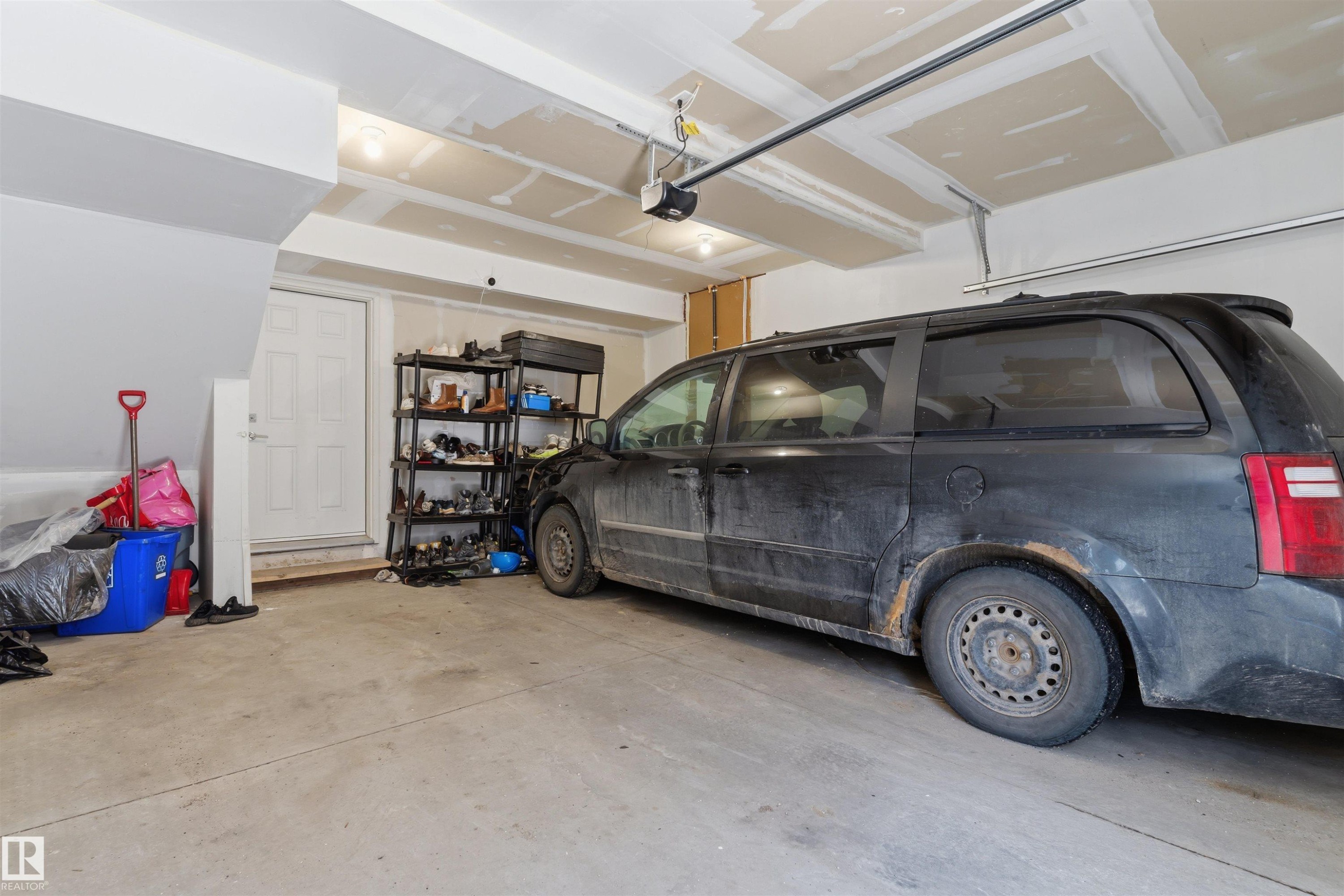 Attached single-car garage featuring a concrete floor, white interior access door, and exposed ceiling joists - 170 804 Welsh Drive, Edmonton, AB