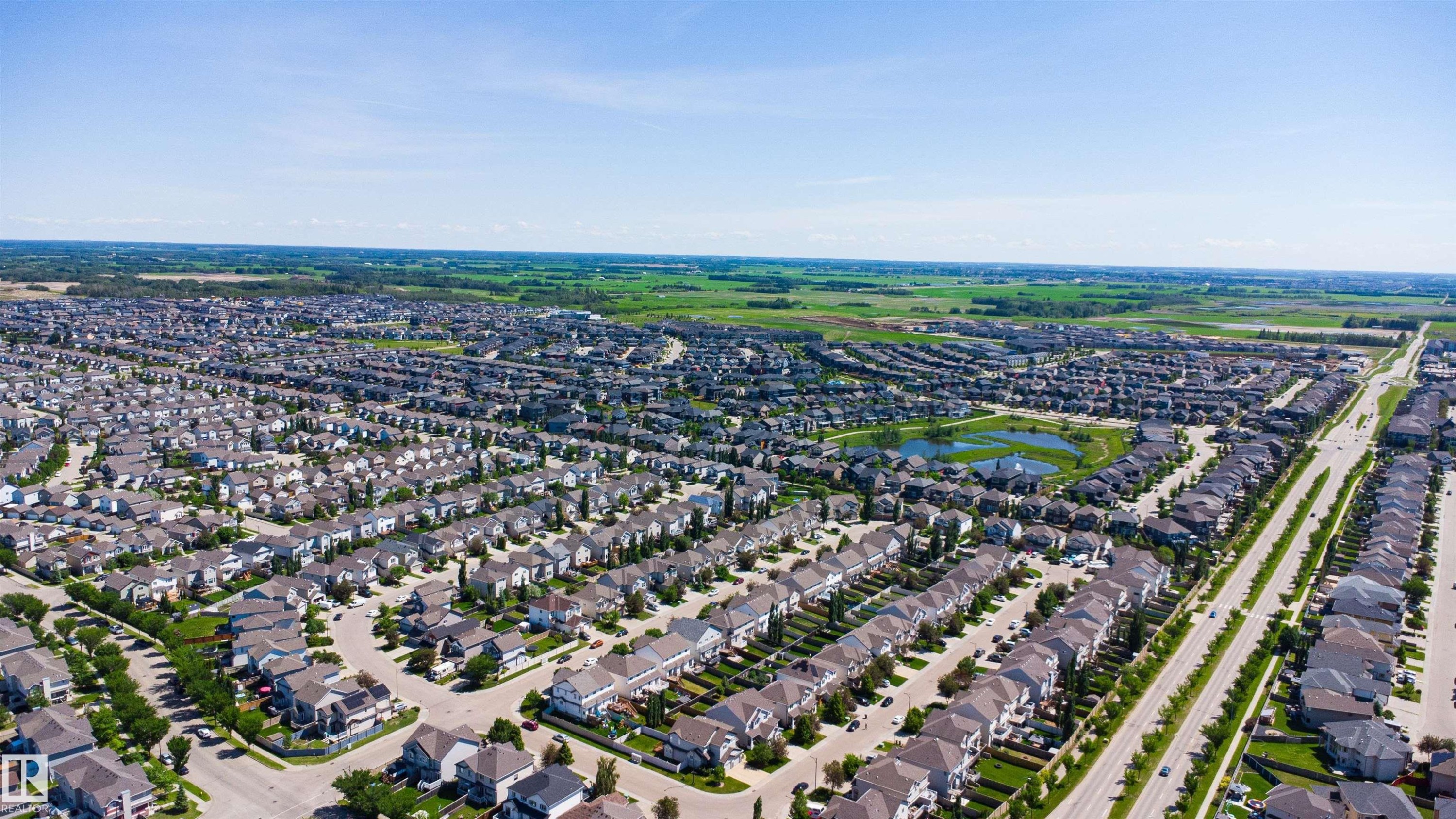 Expansive residential development featuring numerous single-family homes with varied architectural styles, a central retention pond, and broad roadways - 170 804 Welsh Drive, Edmonton, AB