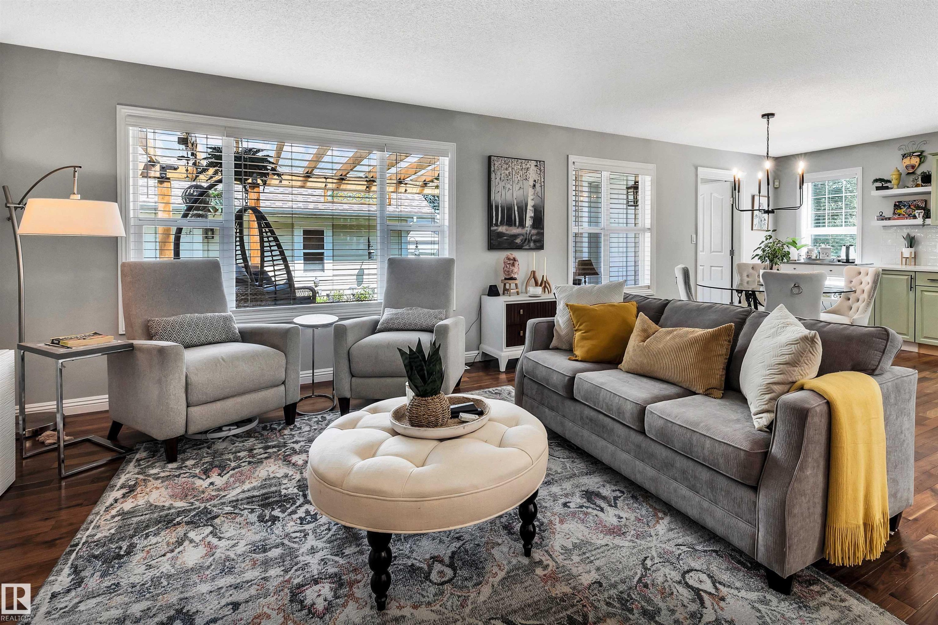 Open-concept living space featuring wood-finish flooring, a large window with horizontal blinds, and recessed lighting - 9804 145 Avenue, Edmonton, AB