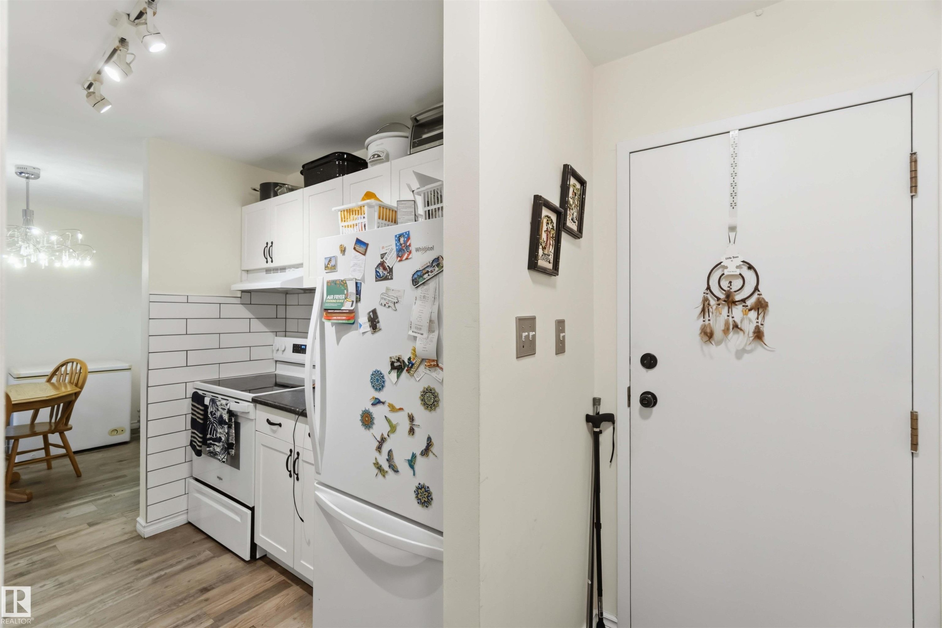 Kitchen area featuring white cabinetry, a subway tile backsplash, and wood-finish flooring - 204 4601 131 Avenue, Edmonton, AB