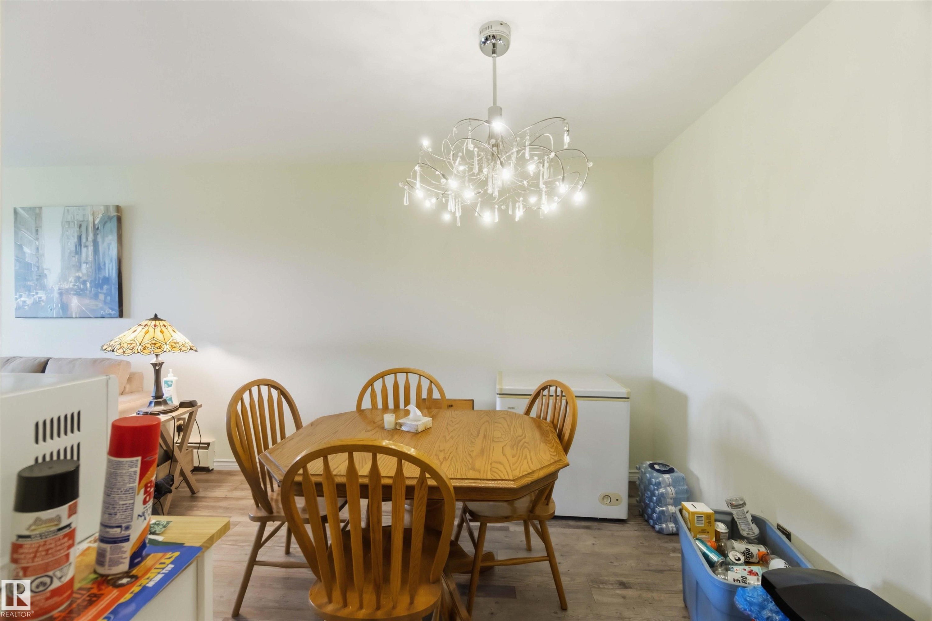 Dining area featuring a contemporary chandelier, light-toned walls, and wood-finish flooring - 204 4601 131 Avenue, Edmonton, AB