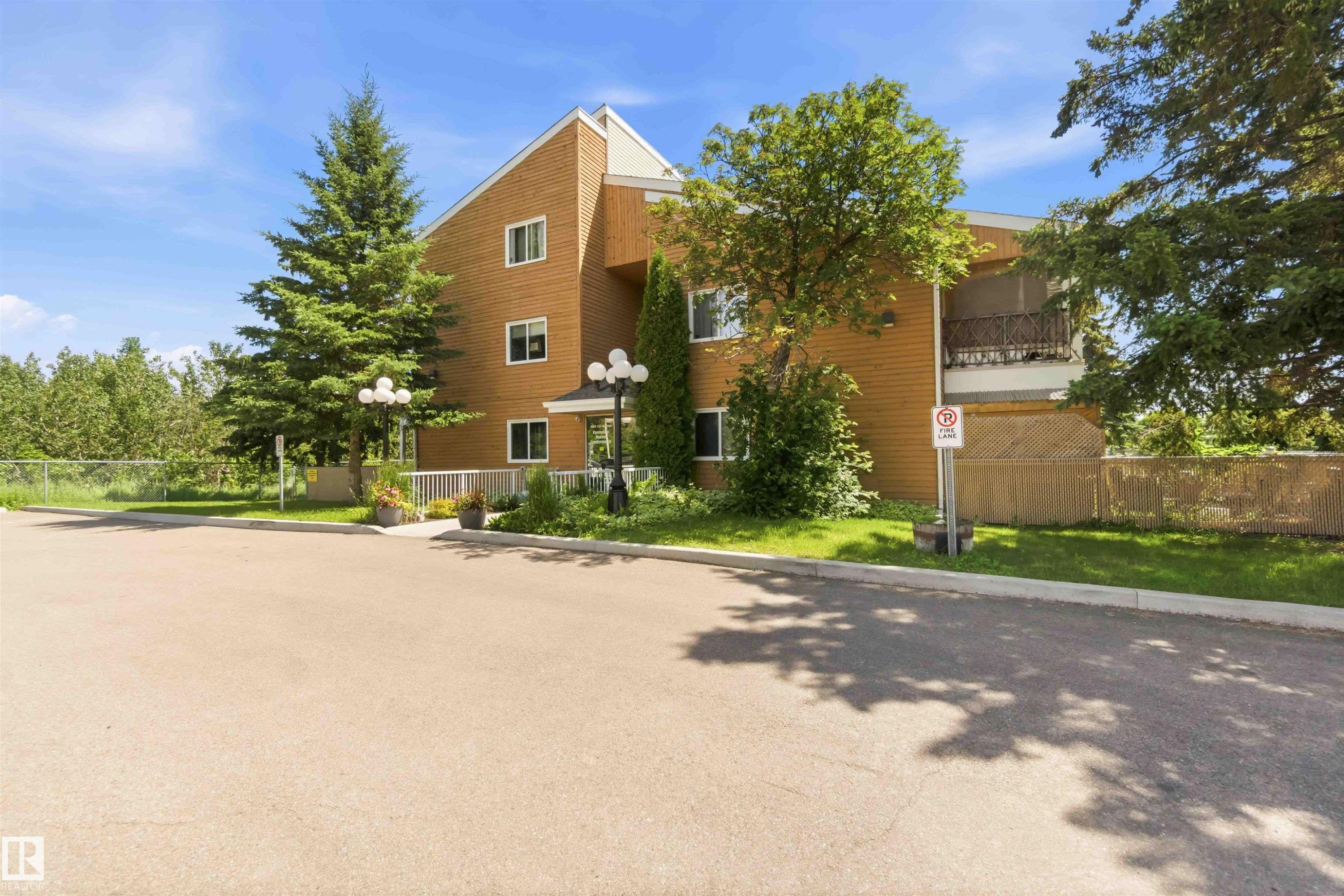 Multi-story building featuring horizontal siding, multiple windows, and a private balcony with ornate railing - 204 4601 131 Avenue, Edmonton, AB