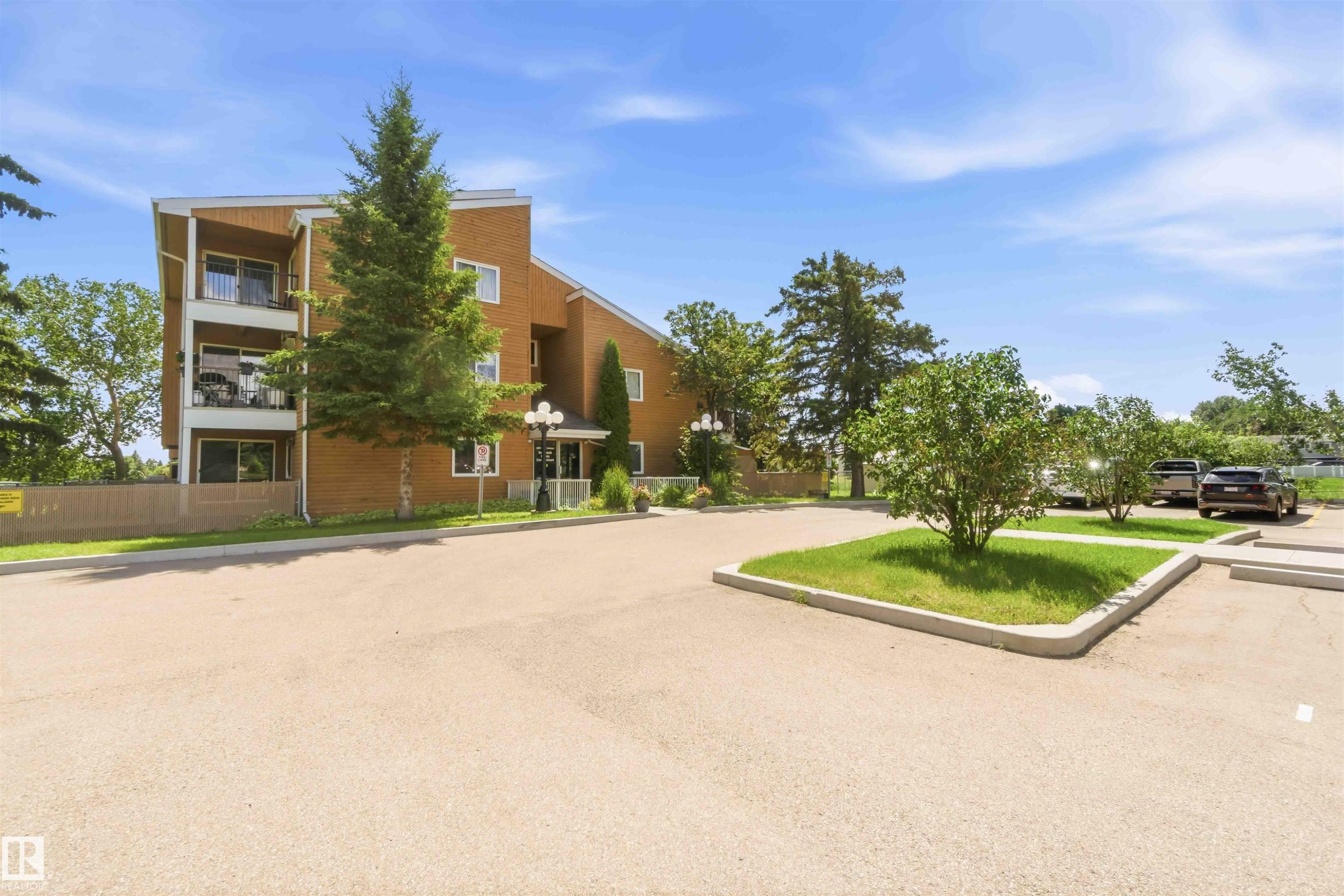 Multi-story brick exterior with balconies and a paved parking area - 204 4601 131 Avenue, Edmonton, AB