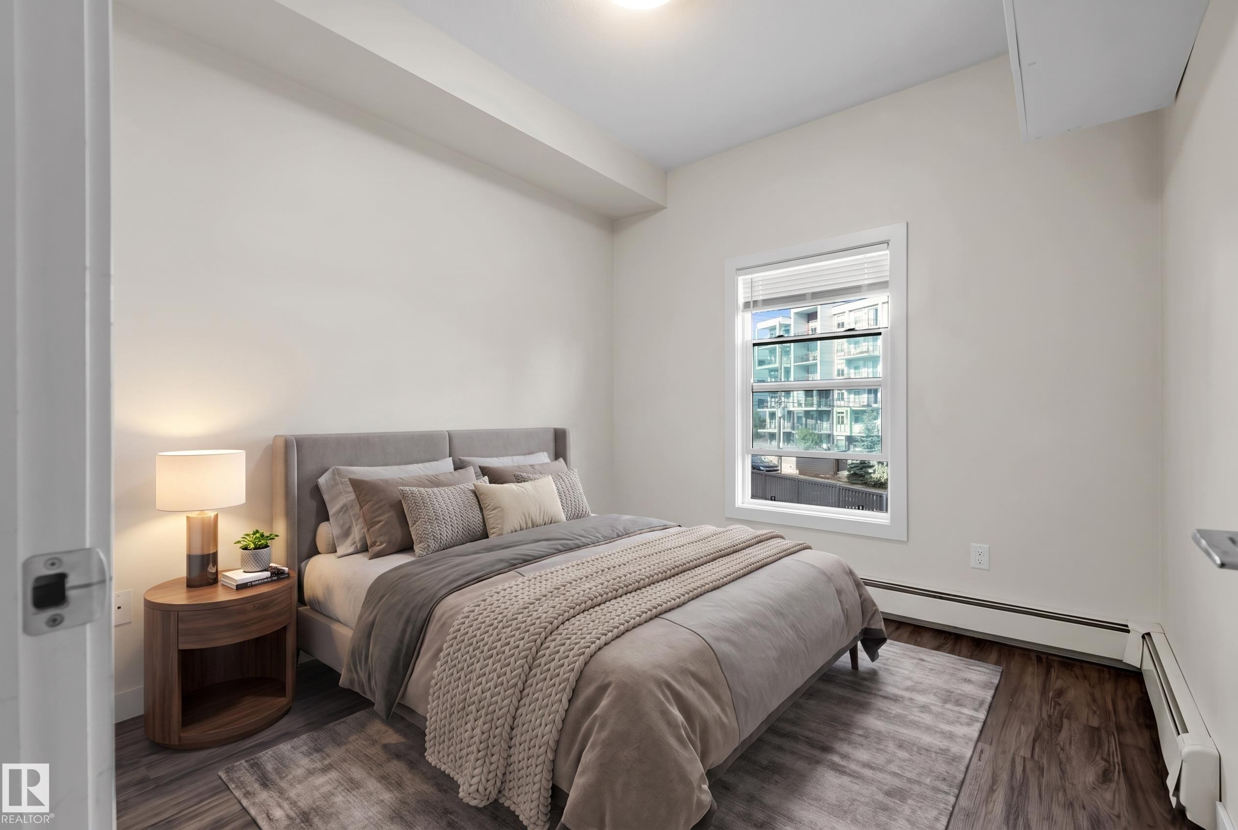 Spacious room featuring wood-finish flooring, a contemporary window, white baseboard heating, and recessed lighting - #209 10611 117 St Nw, Edmonton, AB - Indoor Photo Showing Bedroom