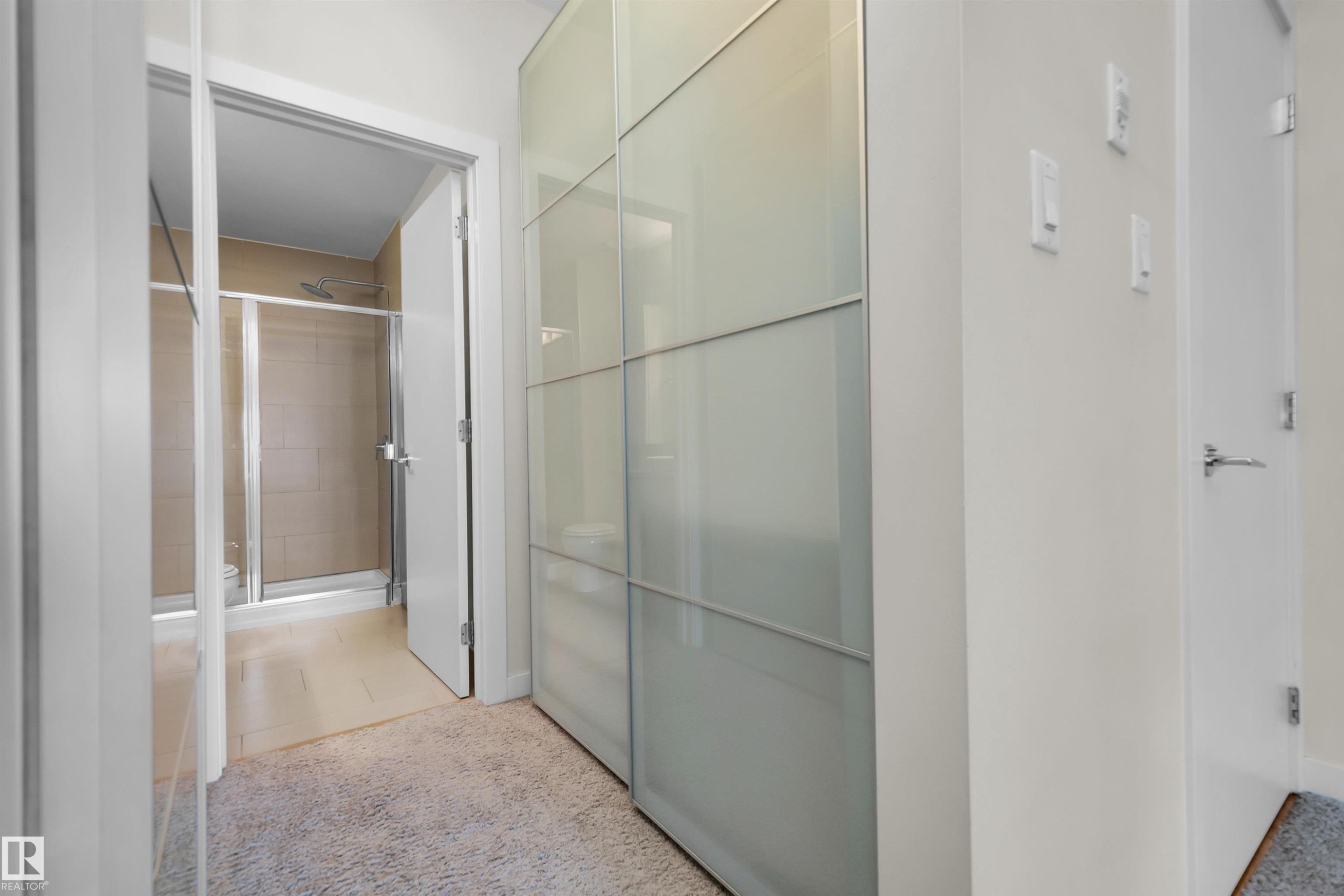 Walk-in shower with clear glass enclosure and light-toned tile surround - #209 10611 117 St Nw, Edmonton, AB - Indoor Photo Showing Other Room