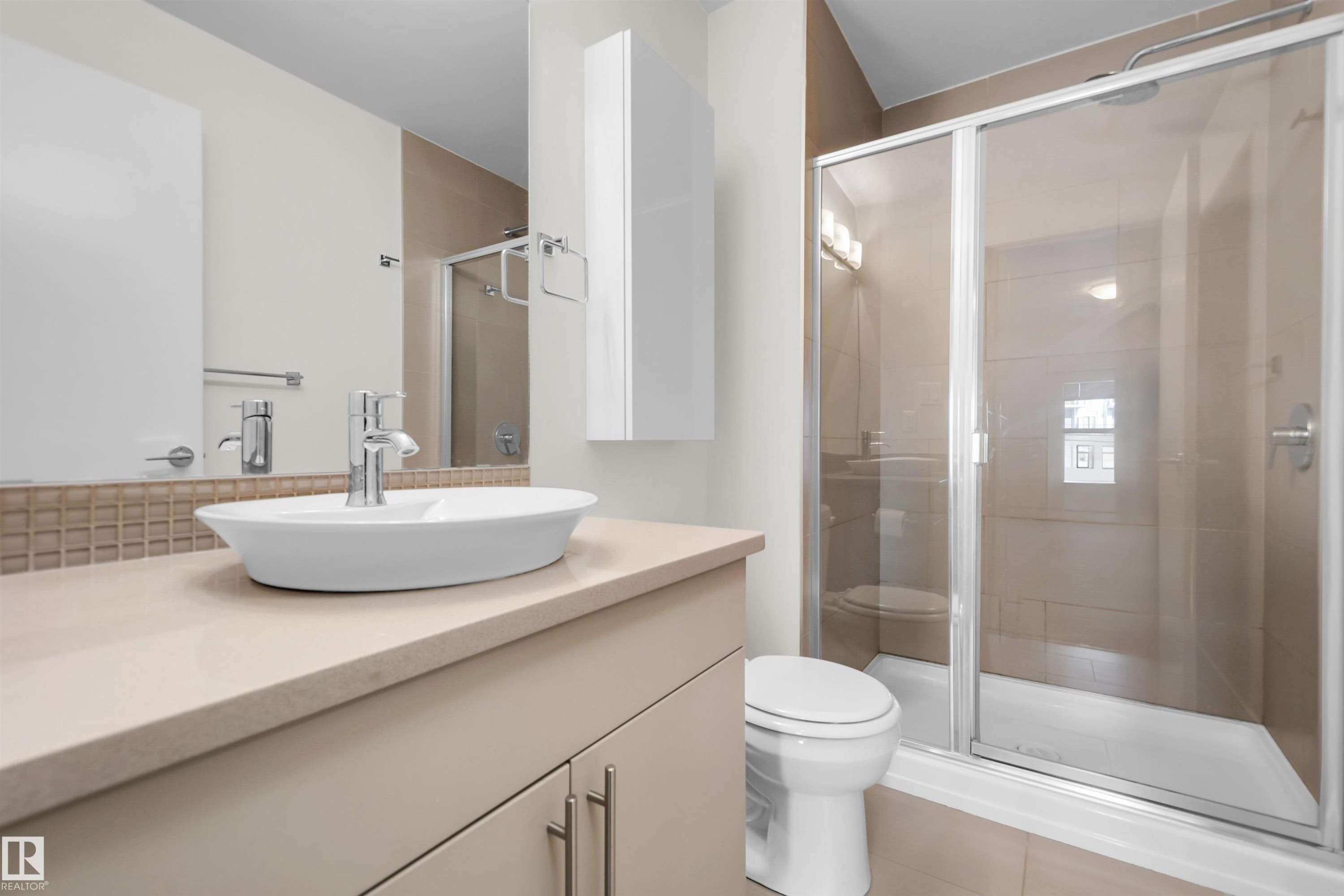 Bathroom featuring a glass-enclosed shower, a vessel sink with chrome faucet, a vanity with under-sink storage, and a wall-mounted storage cabinet - #209 10611 117 St Nw, Edmonton, AB - Indoor Photo Showing Bathroom