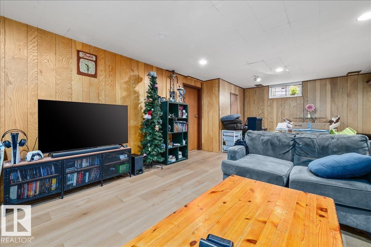 Recreation area featuring wood-panel walls, light wood-finish flooring, and a drop ceiling with recessed lighting - 8736 72 Street Nw, Edmonton, AB - Indoor Photo Showing Basement