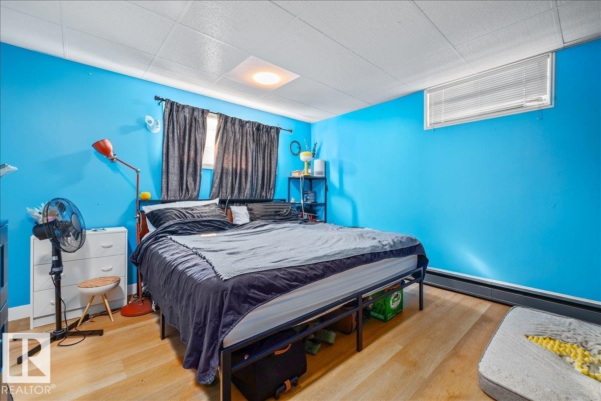 Bedroom featuring bright blue walls and wood-finish flooring - 8736 72 Street Nw, Edmonton, AB - Indoor Photo Showing Bedroom
